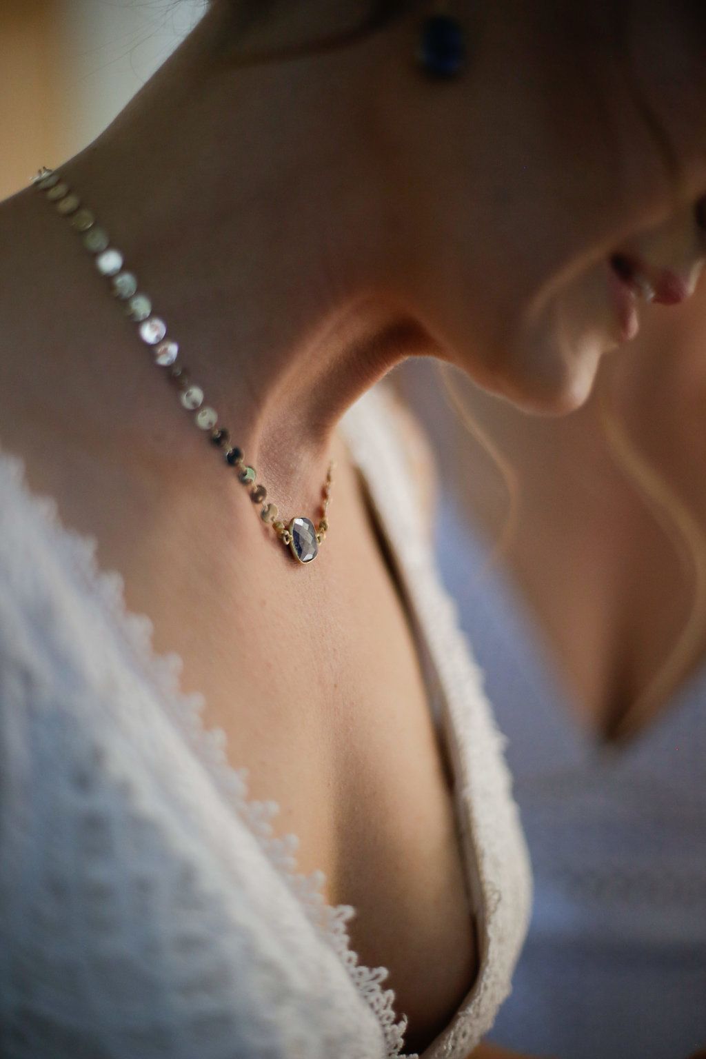Delicate crystal earrings and lace details on a wedding dress neckline.