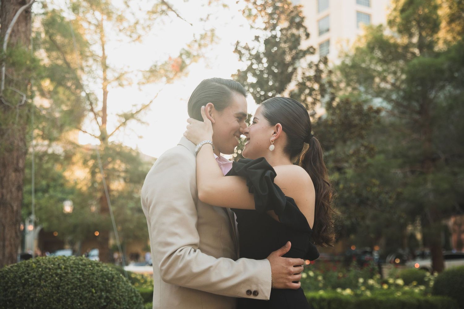 A tender romantic moment between a couple during sunset in an urban garden setting.