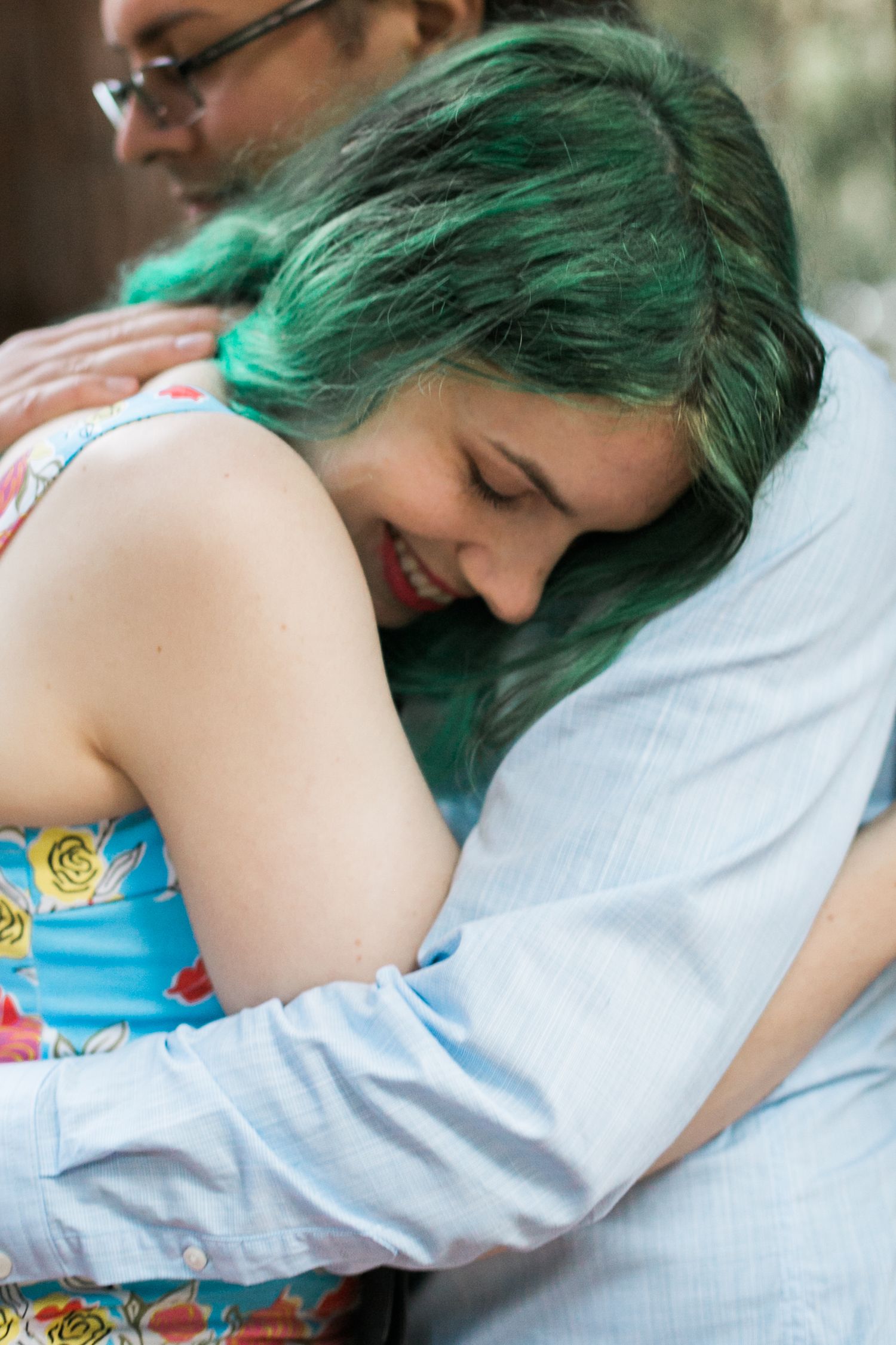 Couple sharing an intimate embrace outdoors, one with vibrant green hair.