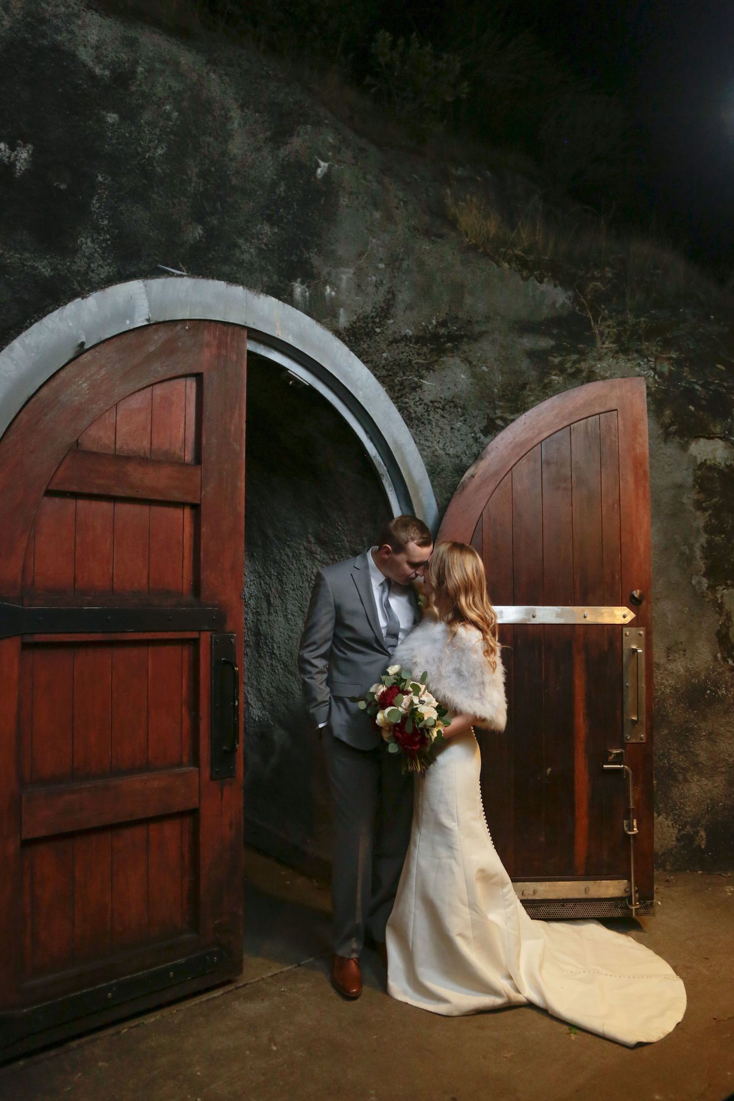 Rustic wine cellar entrance with arched wooden doors and stone walls creates romantic ambiance.