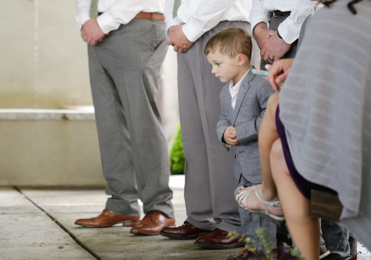 Lower body view of wedding party members in gray suits and dresses.