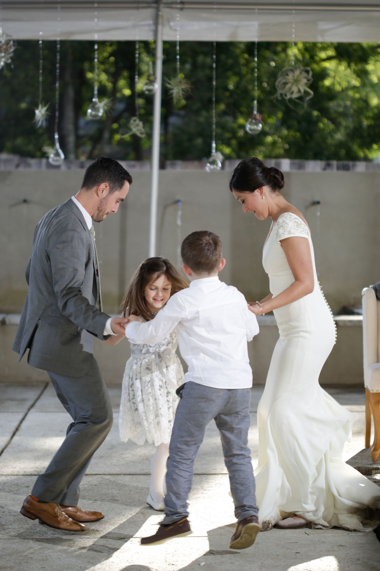 A family dances together under hanging lights at a wedding reception.