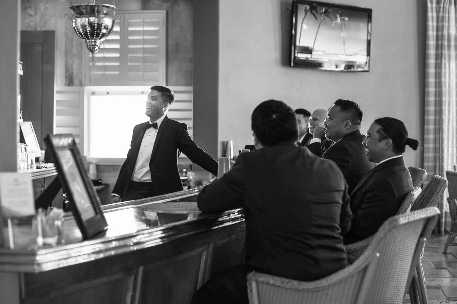 Bartender and patrons interact at an elegant bar counter in monochrome.