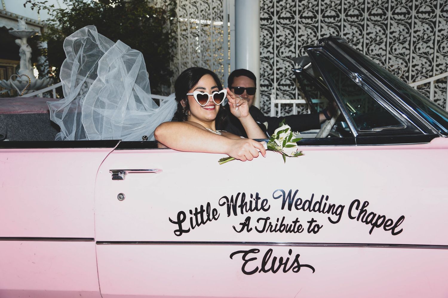 Pink vintage car with 'Little White Wedding Chapel' and 'Elvis' text displayed.