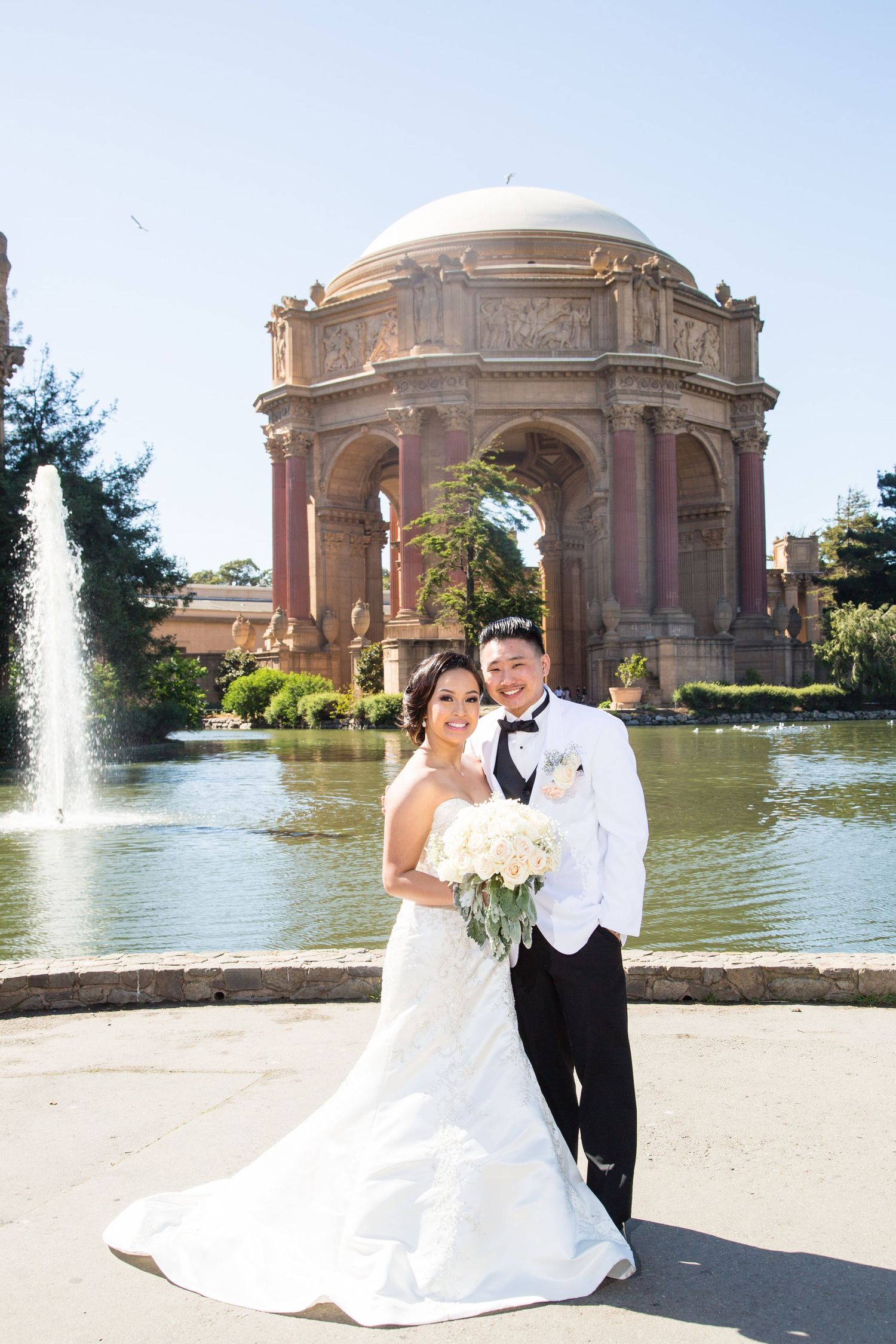 Newlyweds pose in front of the Palace of Fine Arts with its iconic dome and reflecting pool.
