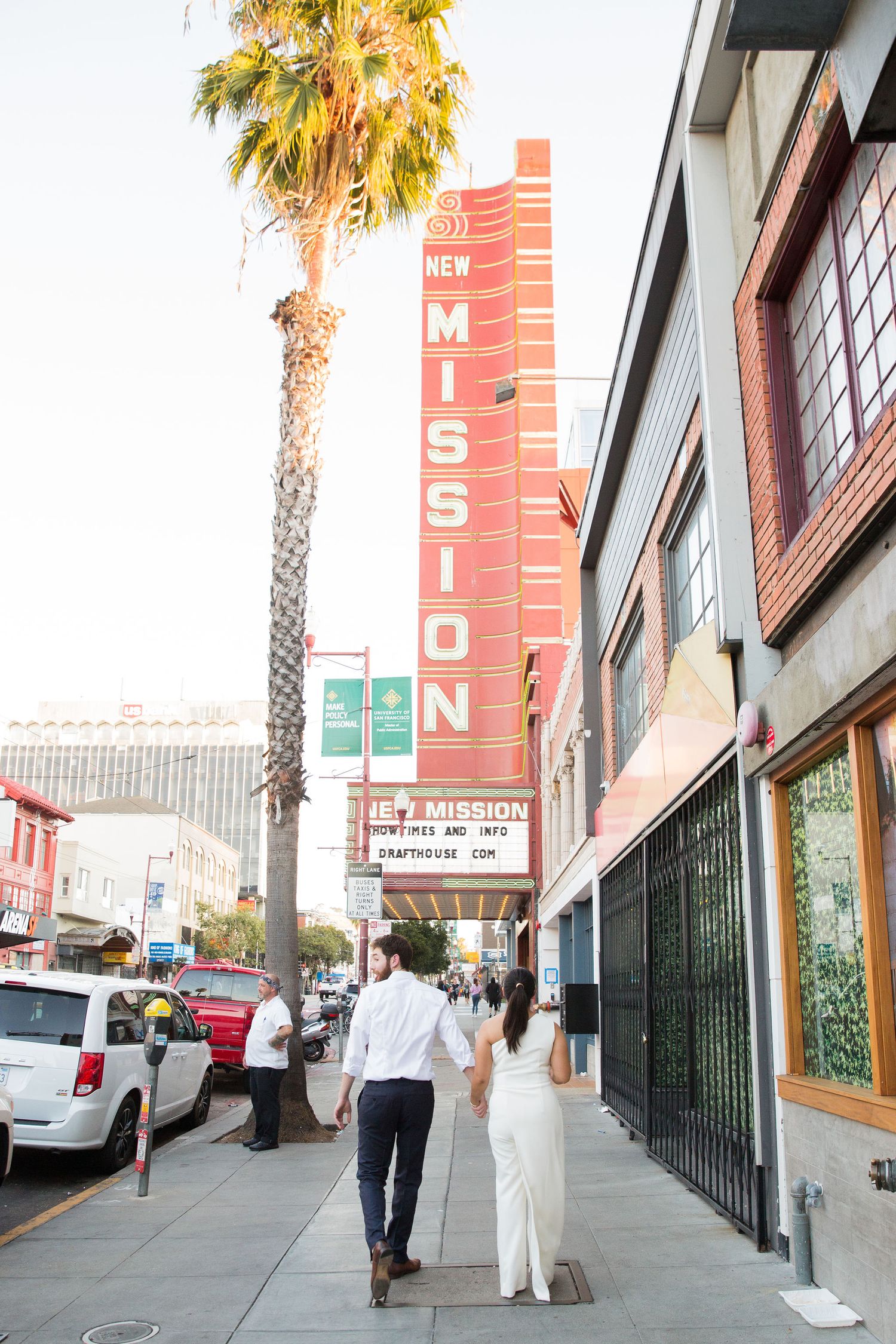Urban street scene with palm trees and vintage storefront signage.