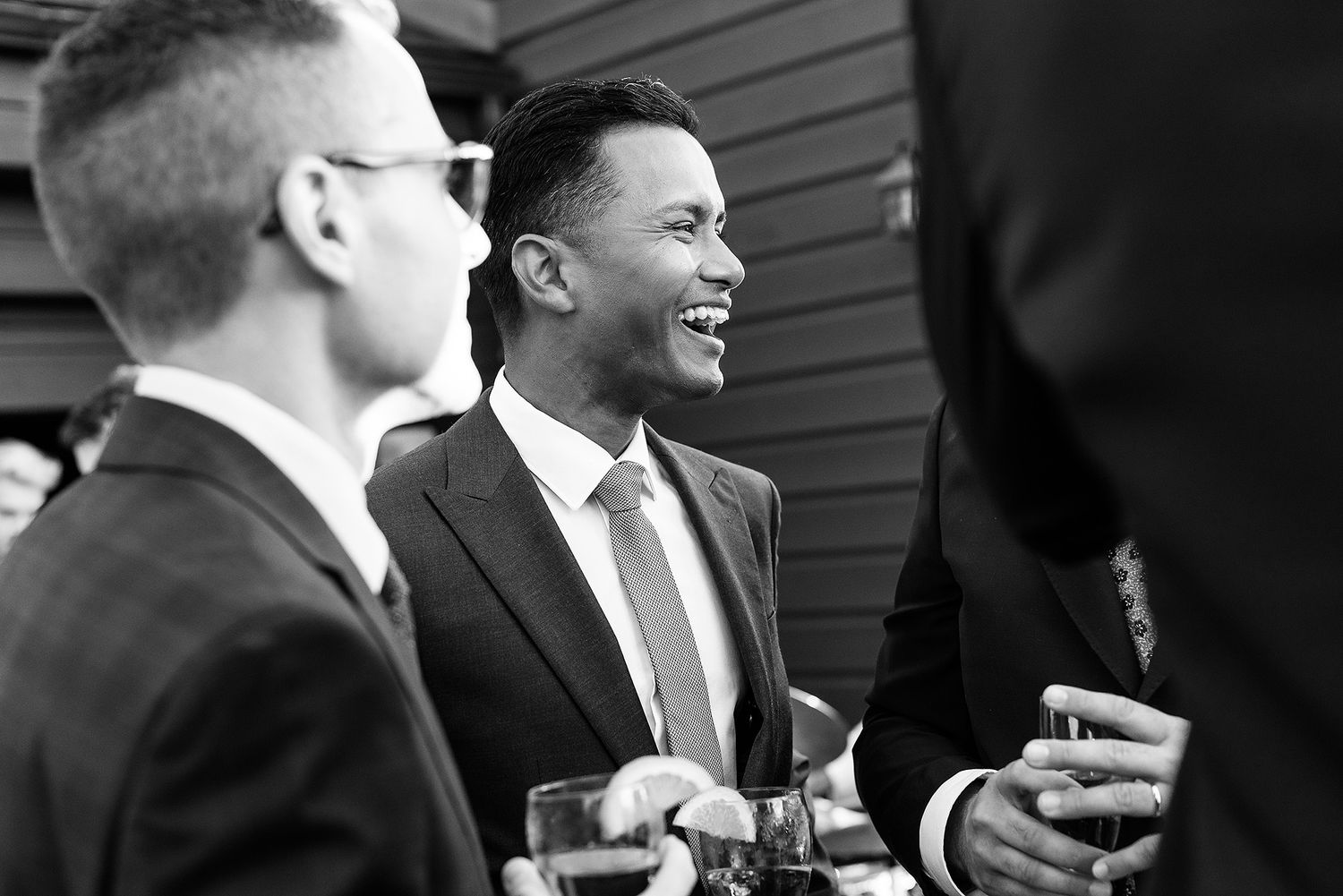 A black and white photo shows two people in business suits laughing and socializing during a gathering event. Grand Lodge.