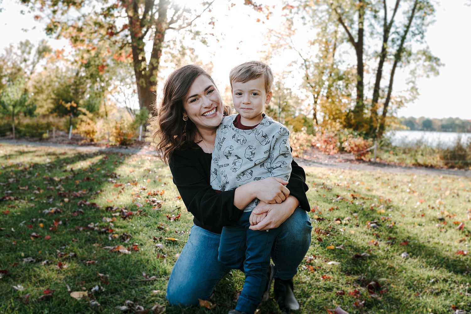 A heartwarming outdoor autumn portrait taken in a park with fall foliage and sunlight filtering through the trees.