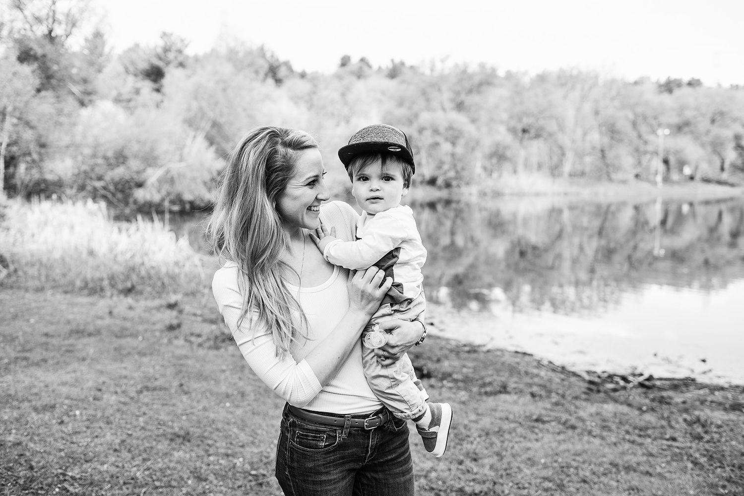 A black and white photo of a parent and child sharing a tender moment by a serene lake.