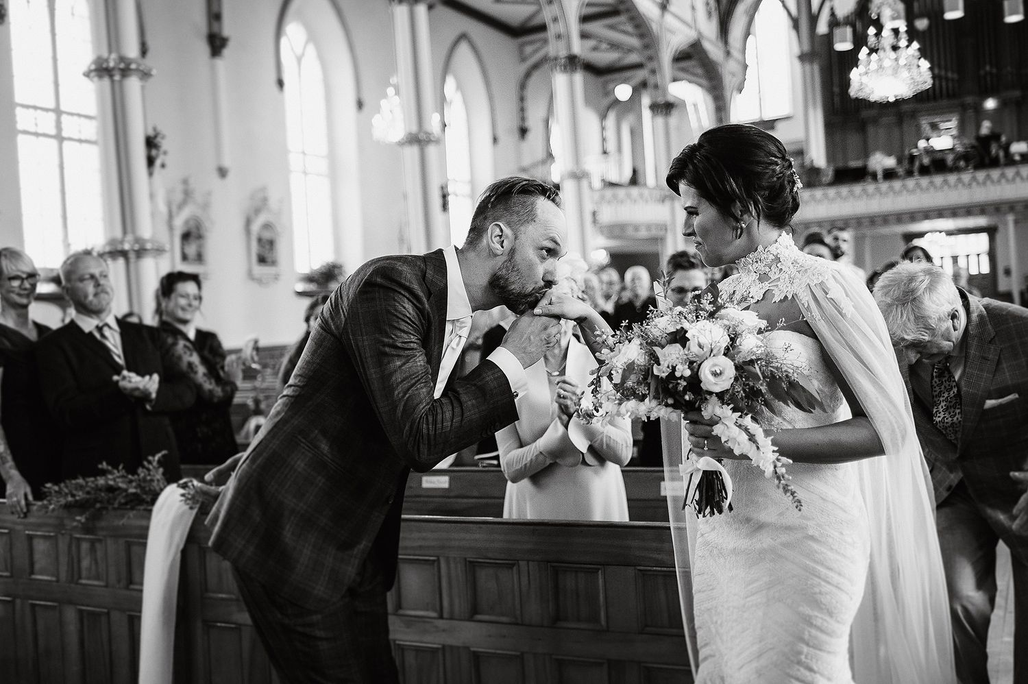 A black and white candid moment captures a joyful interaction at a traditional church wedding ceremony.