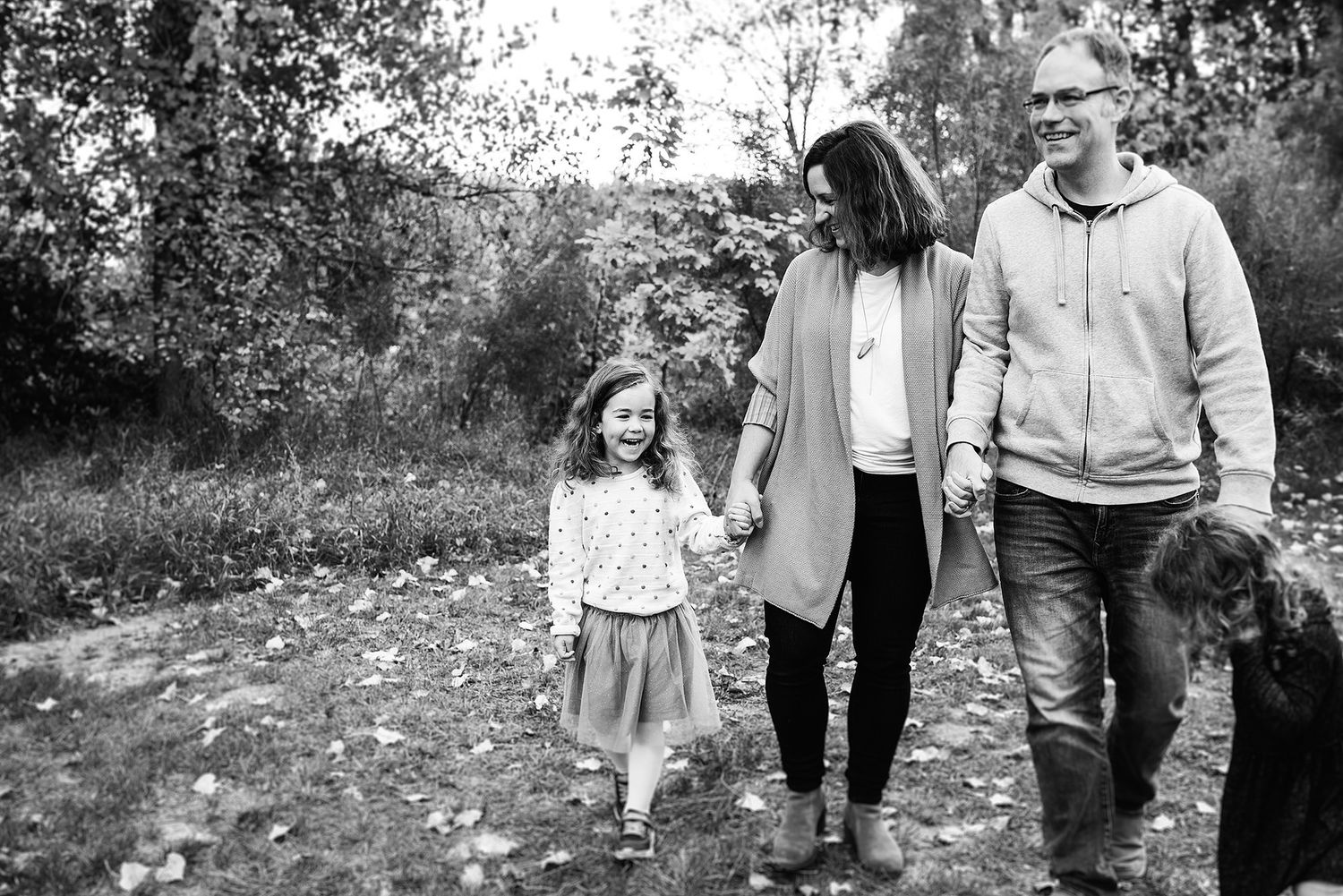 Family walks together with their dog through a scenic wooded area during autumn.