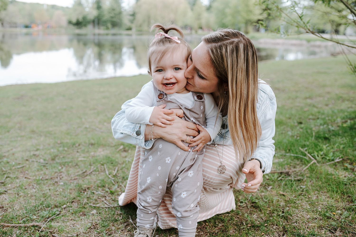 A sweet tender moment between parent and child embracing by a tranquil lake on a spring day.