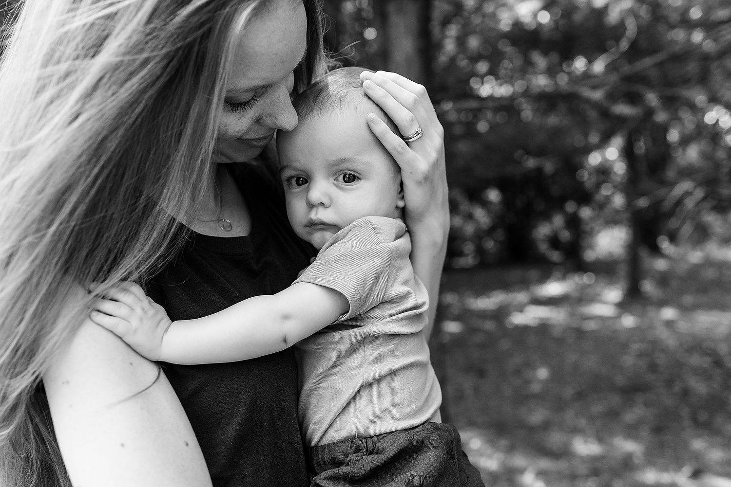 Black and white photo showing an intimate moment between parent and child outdoors.