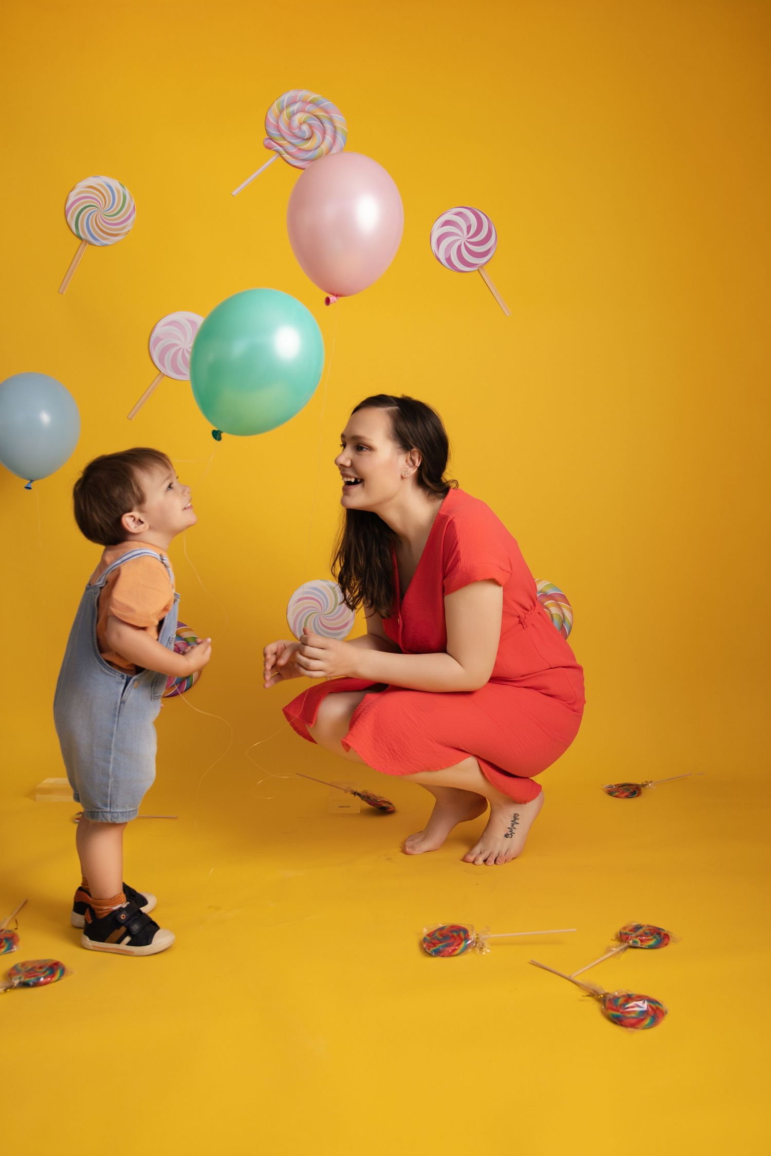 A sequence showing playful interaction with balloons and lollipop props against a vibrant yellow background.