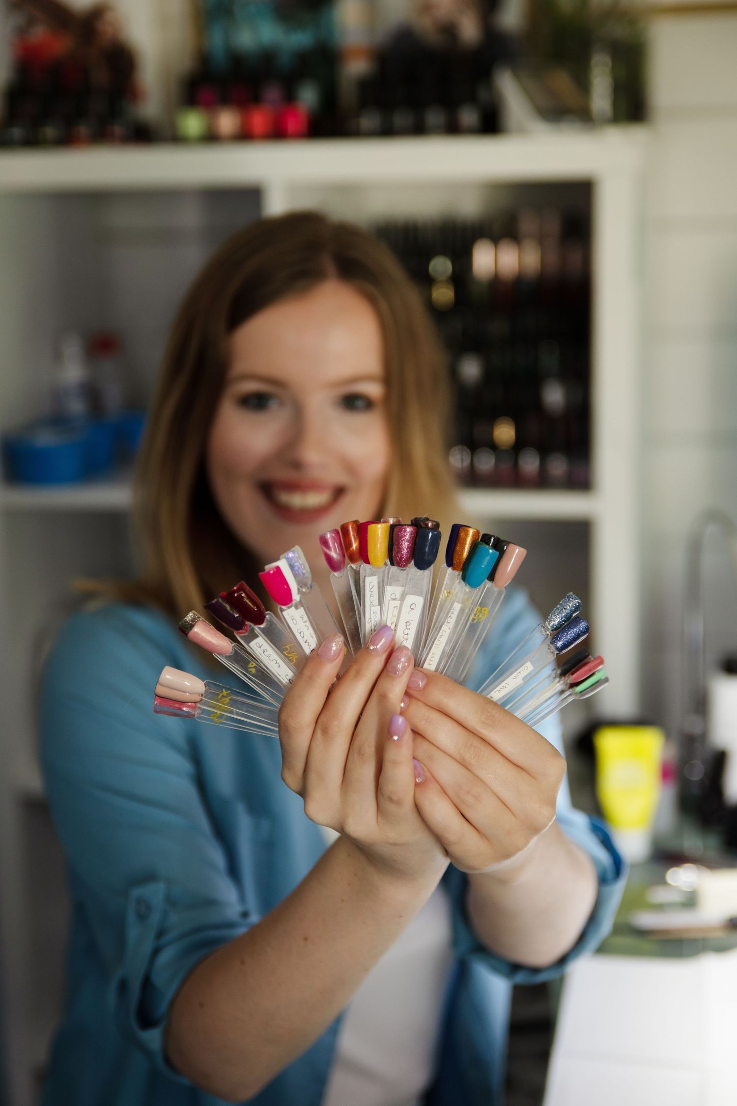 Person holding up colorful nail polish bottles in a fanned out display showing variety of shades.