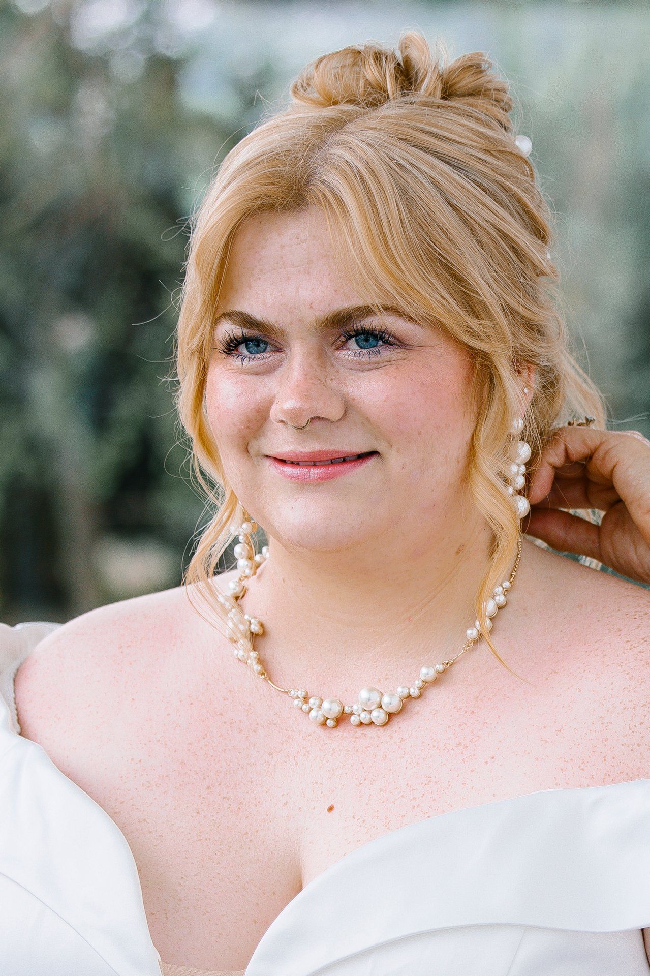 A bridal portrait showcasing soft makeup, pearl necklace and elegant updo hairstyle.