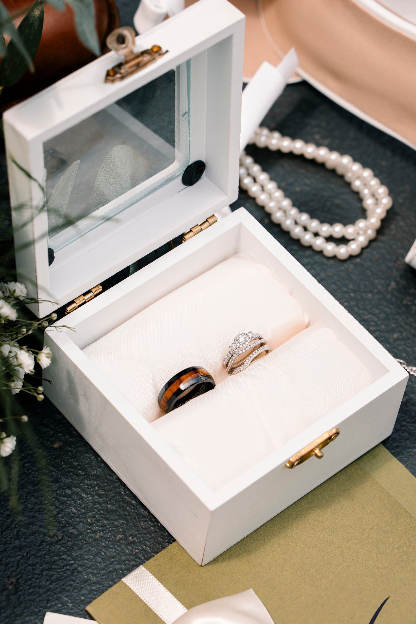 Pearl necklace and jewelry displayed inside a small white box on a dark surface.
