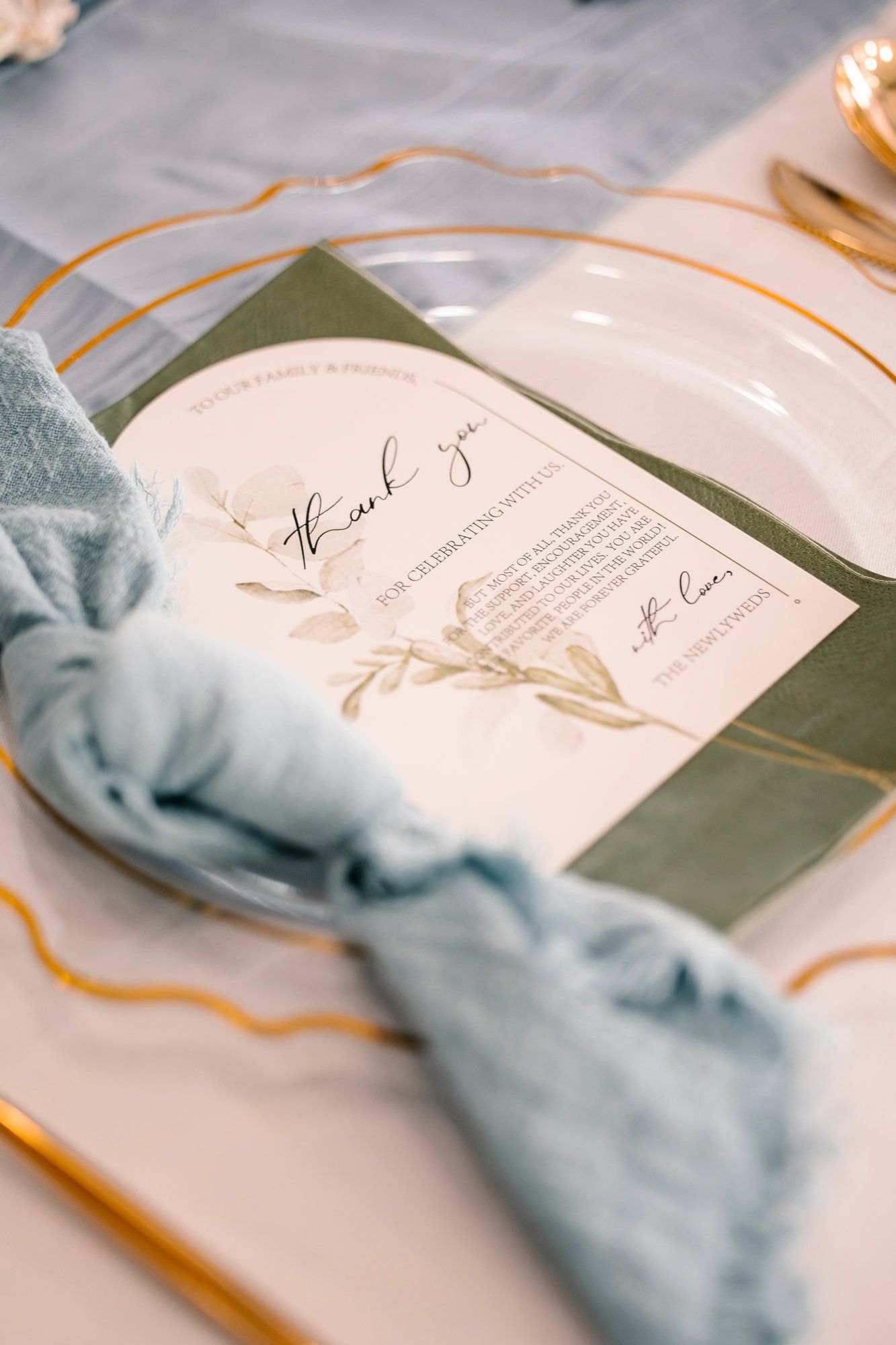 Wedding menu cards with elegant calligraphy and soft blue fabric accents arranged on place settings.
