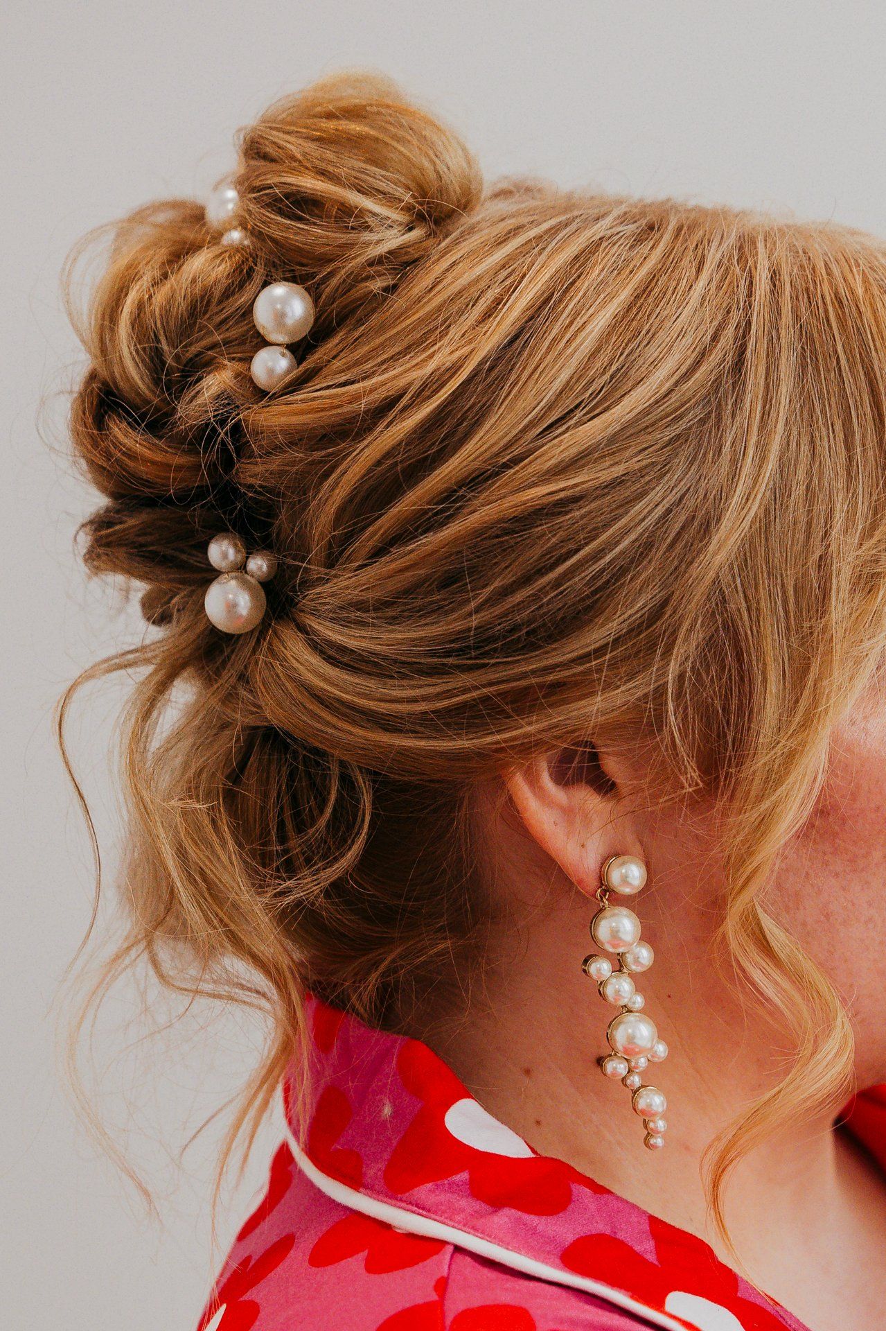 Elegant updo hairstyle adorned with pearl pins and matching cascading pearl earring.