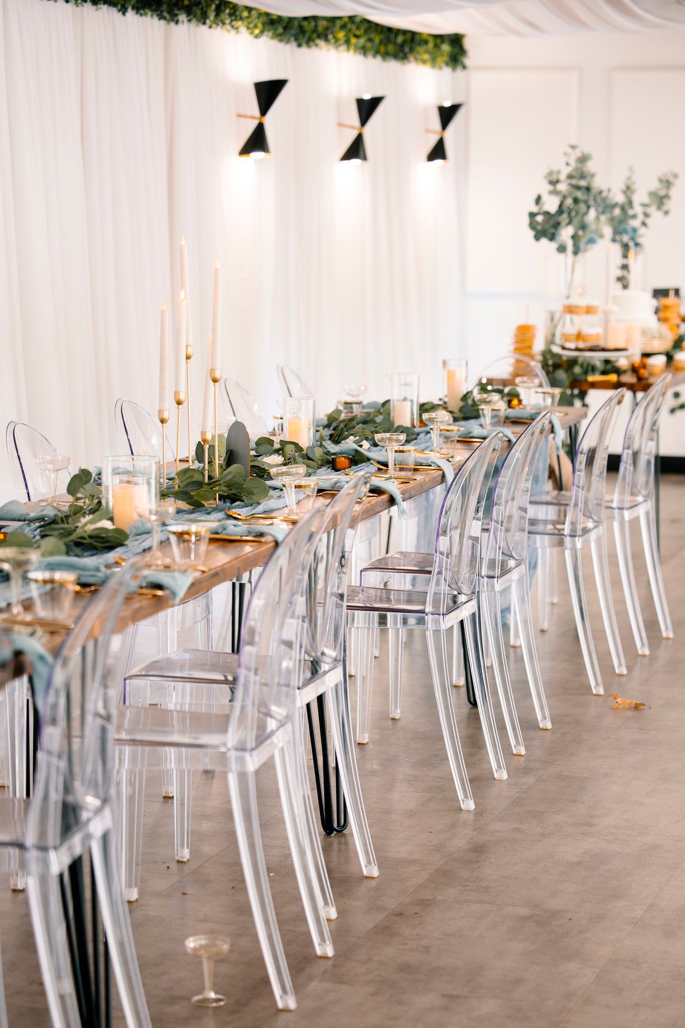 Modern reception setup with transparent ghost chairs arranged in rows under a white tent with elegant table settings.