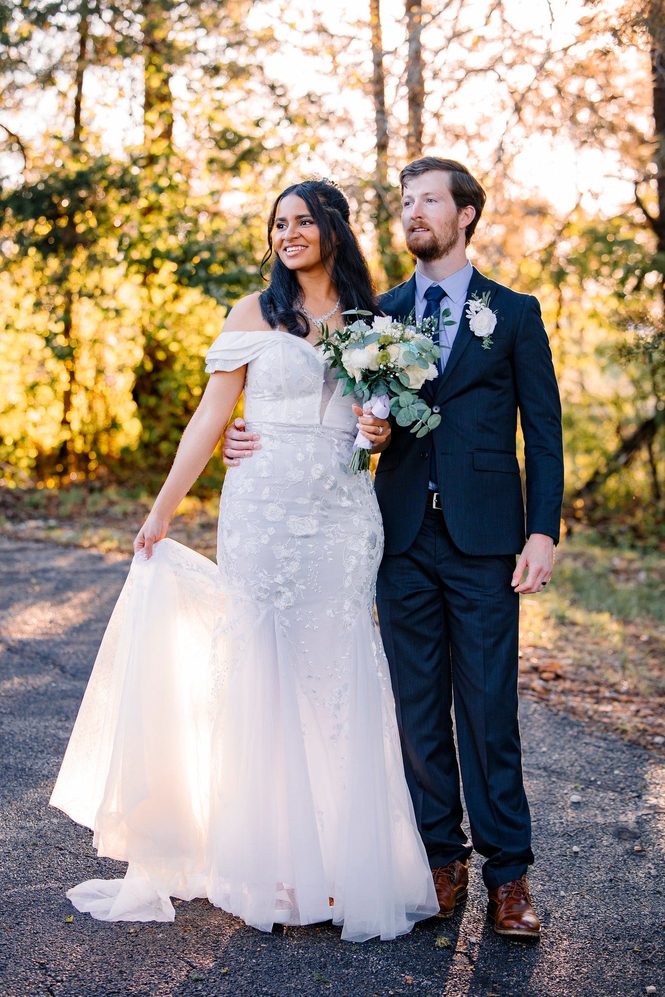 Wedding couple wearing formal attire pose together outdoors during golden hour sunset.