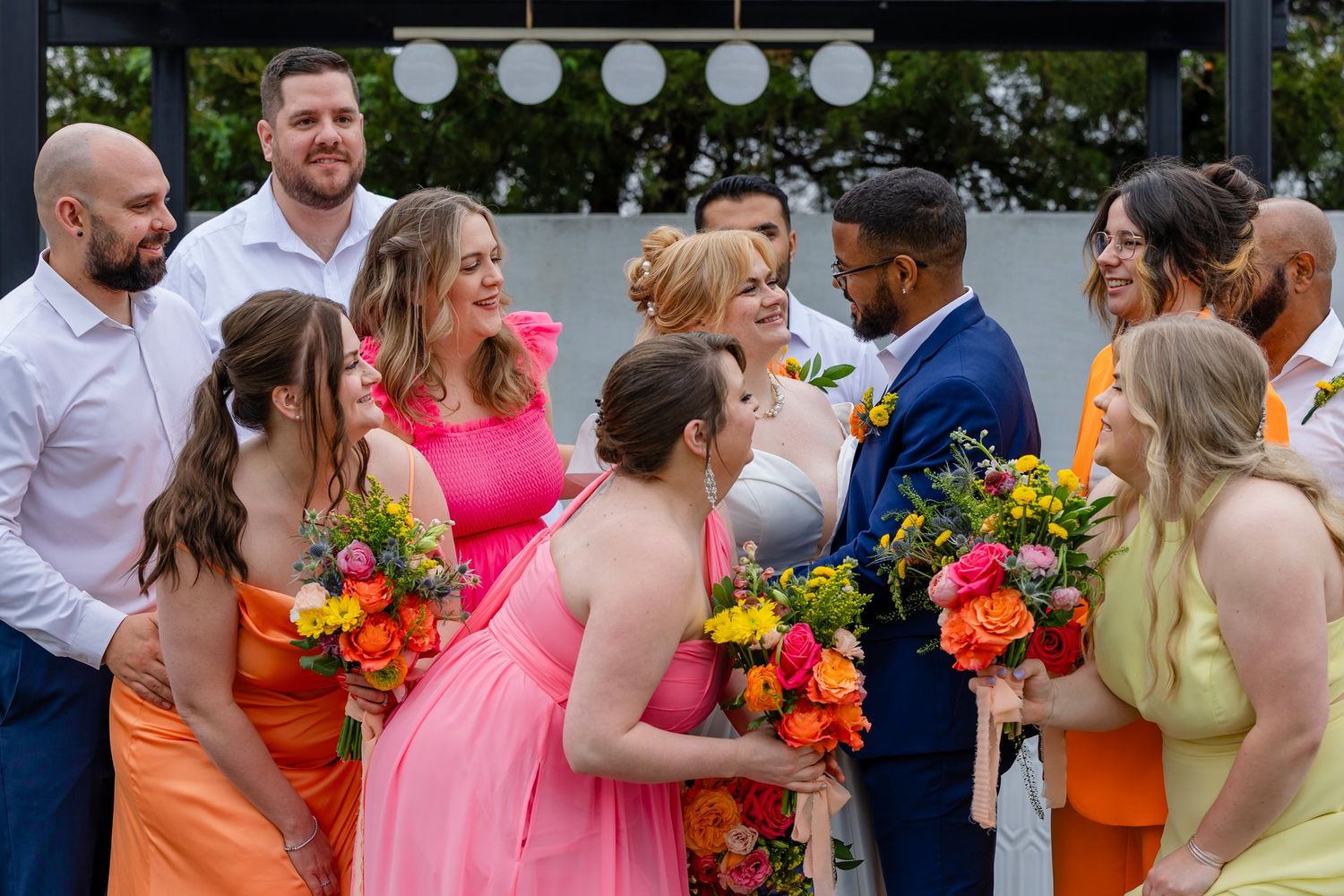 Colorful wedding party celebrating with bride and groom outdoors.