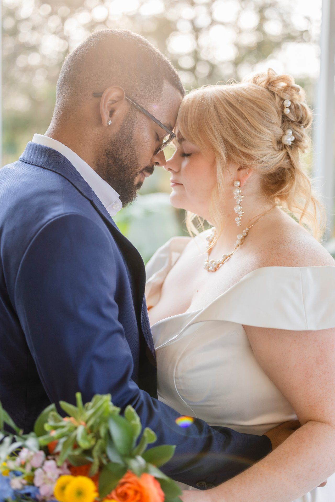 A romantic close-up wedding portrait under soft natural lighting with colorful bouquet details.