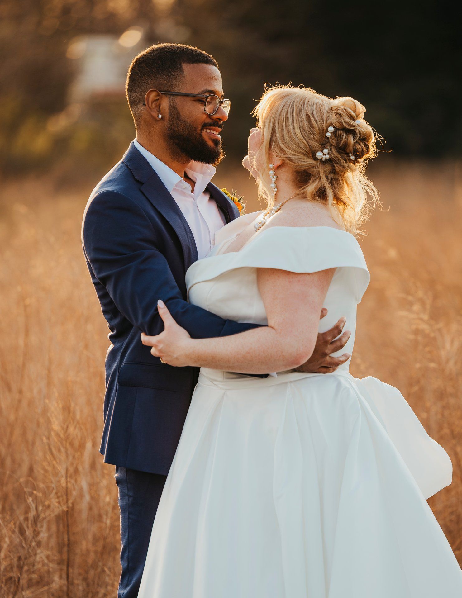 Romantic sunset portrait of newlyweds embracing in a golden field.