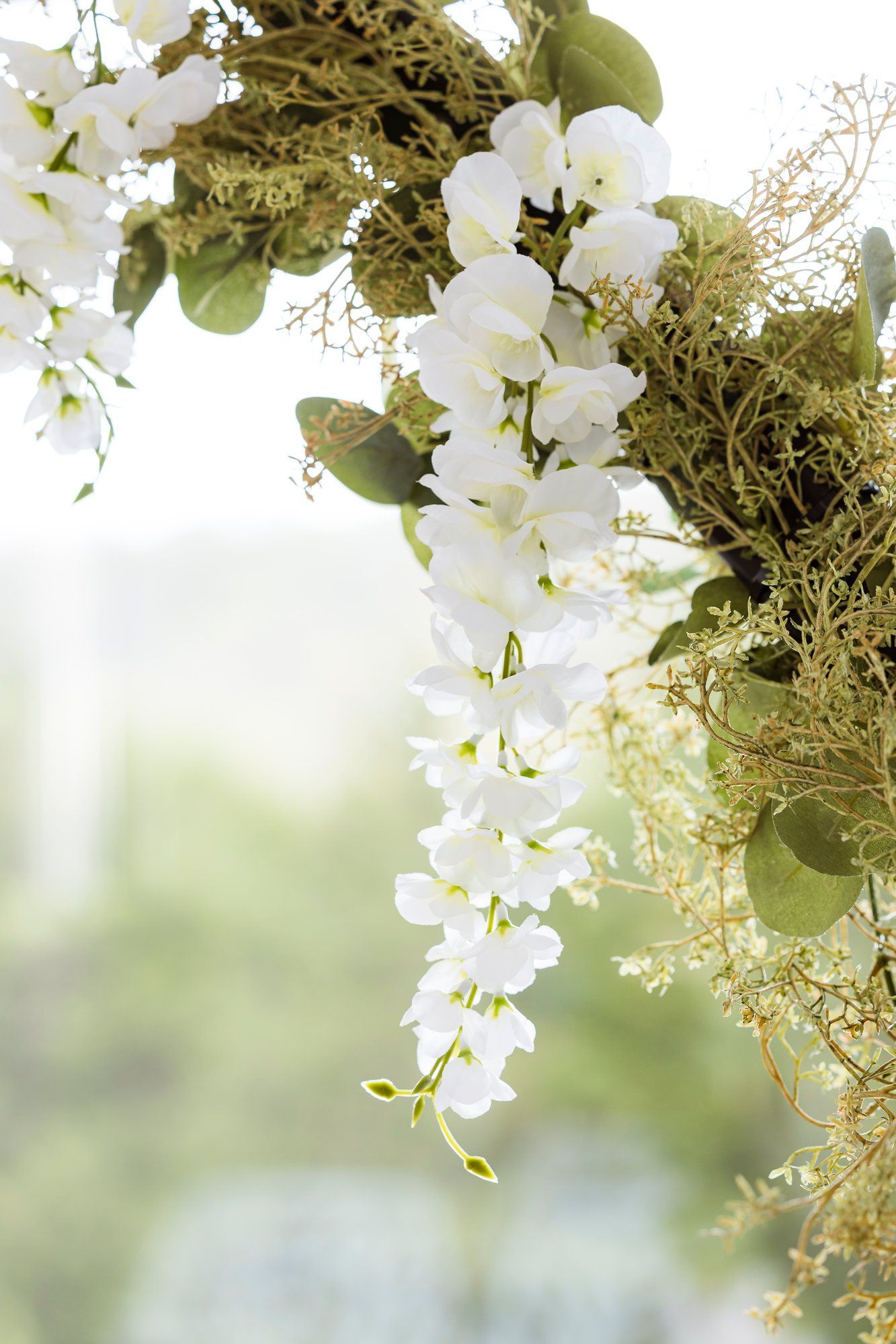 Cascading white orchids and delicate greenery create an ethereal floral display against a soft blurred background.