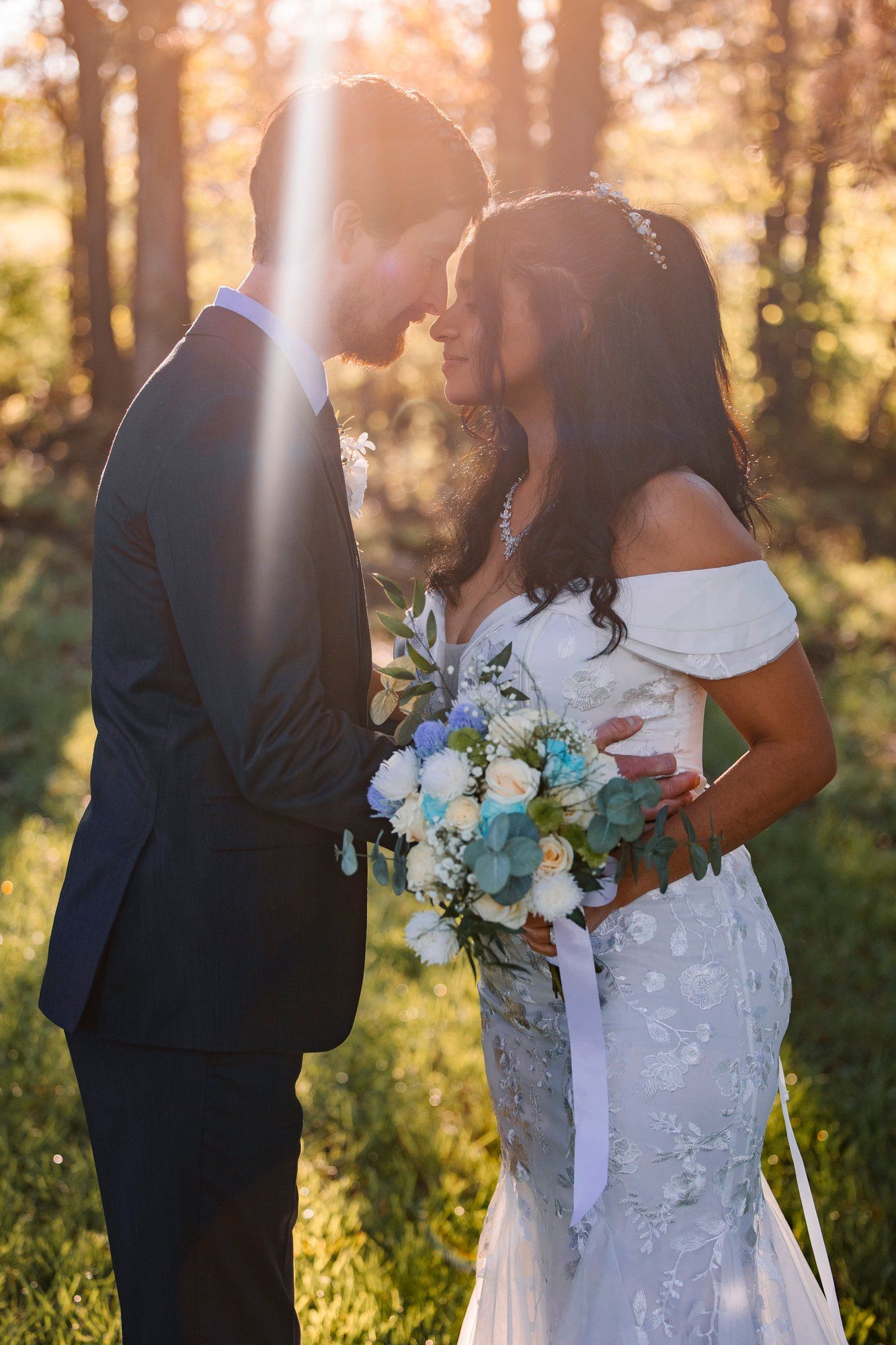 A romantic wedding moment captured in golden sunlight as newlyweds share an intimate moment with a lovely floral bouquet.
