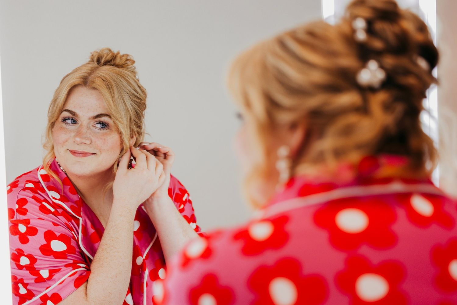 A reflection in a mirror shows someone in a red polka dot robe getting ready for a special occasion.