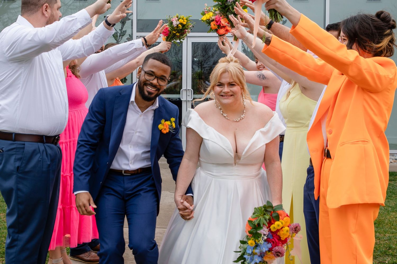 Wedding guests form a celebratory arch for the newlyweds walking beneath.