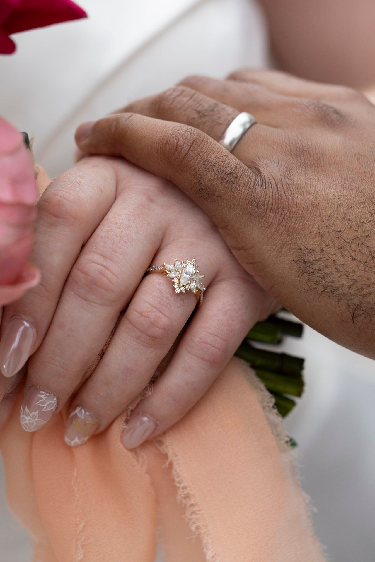 A closeup shot of hands showing a sparkling diamond engagement ring with a gold band on a finger.