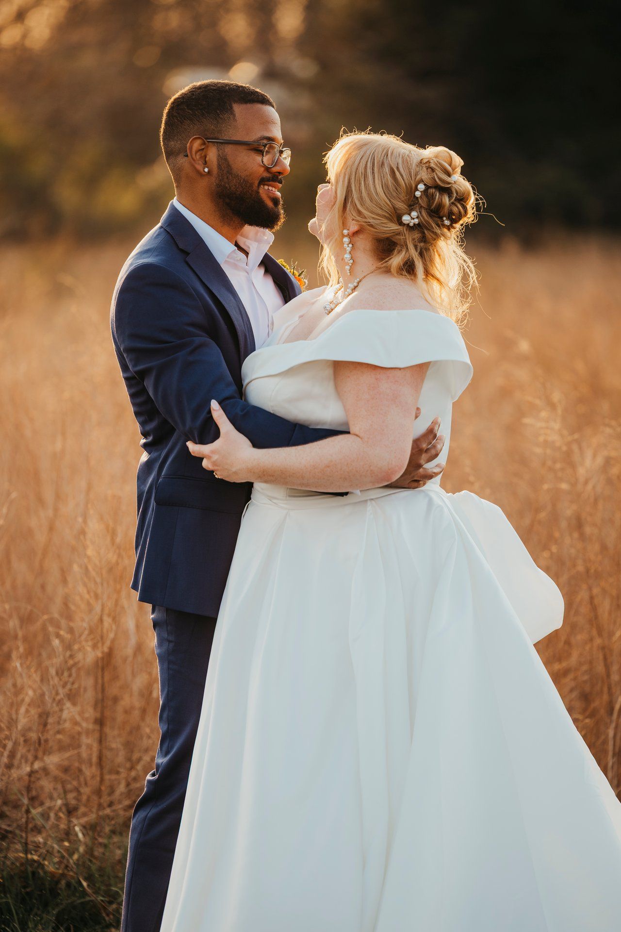 Happy couple laughing together in sunset field during wedding portraits.