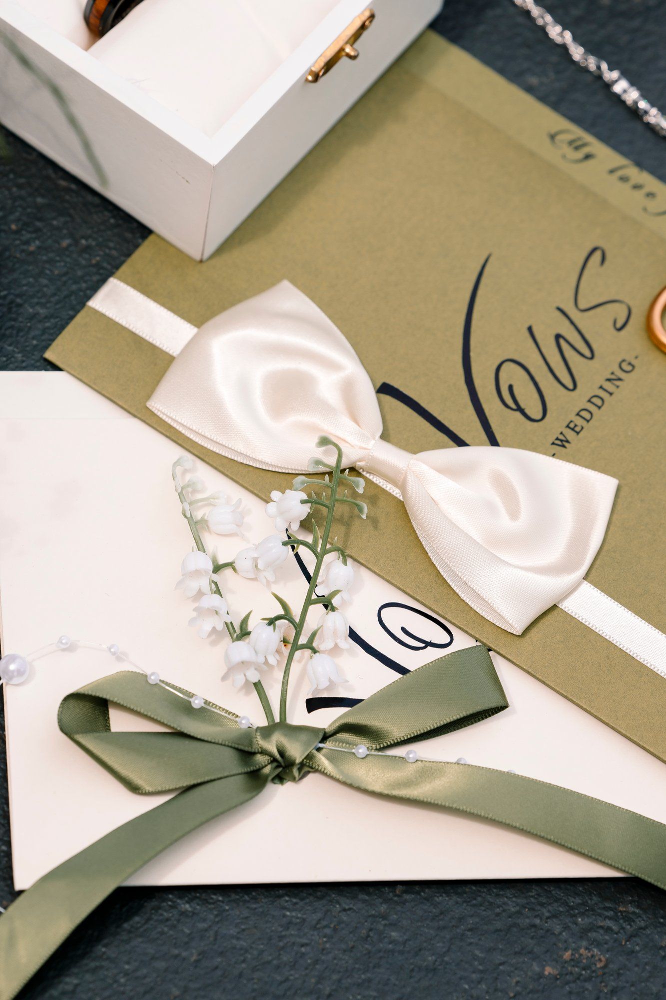 Rustic invitation cards with olive green ribbons and white paper flowers displayed in a series.