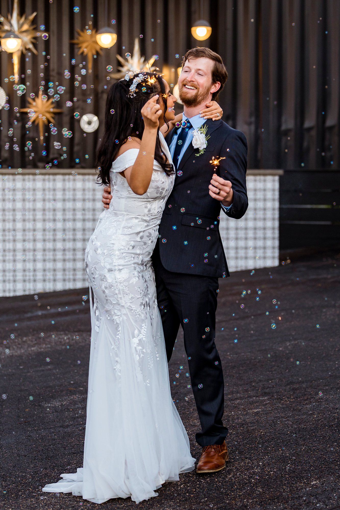 Newlywed couple laughing and celebrating with confetti and starburst decorations at their wedding reception.