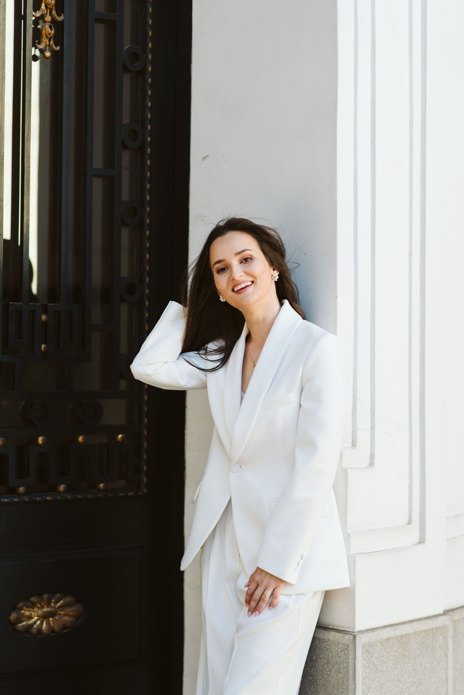 Bride poses against white column with natural lighting. Zagreb