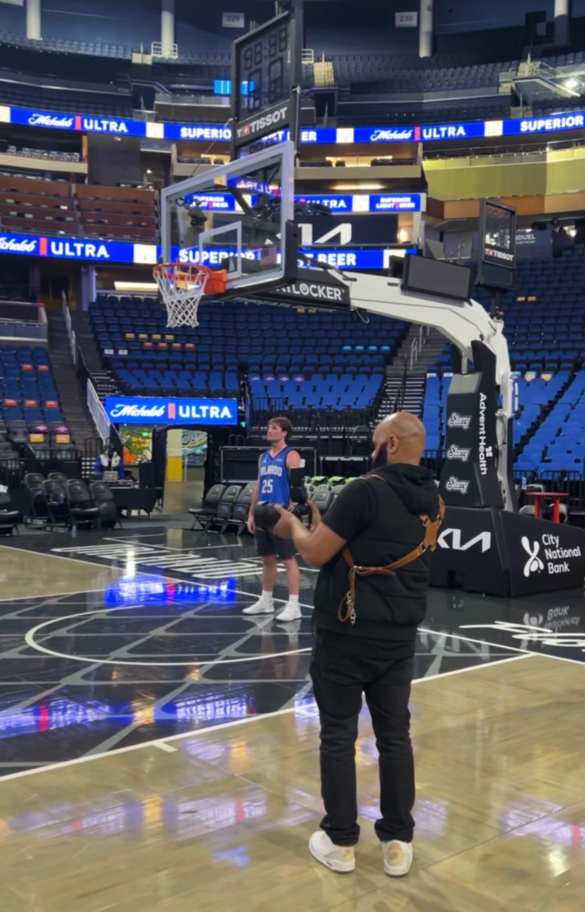 Basketball player practicing on an empty court at an indoor arena with Michelob Ultra signage visible in the background.