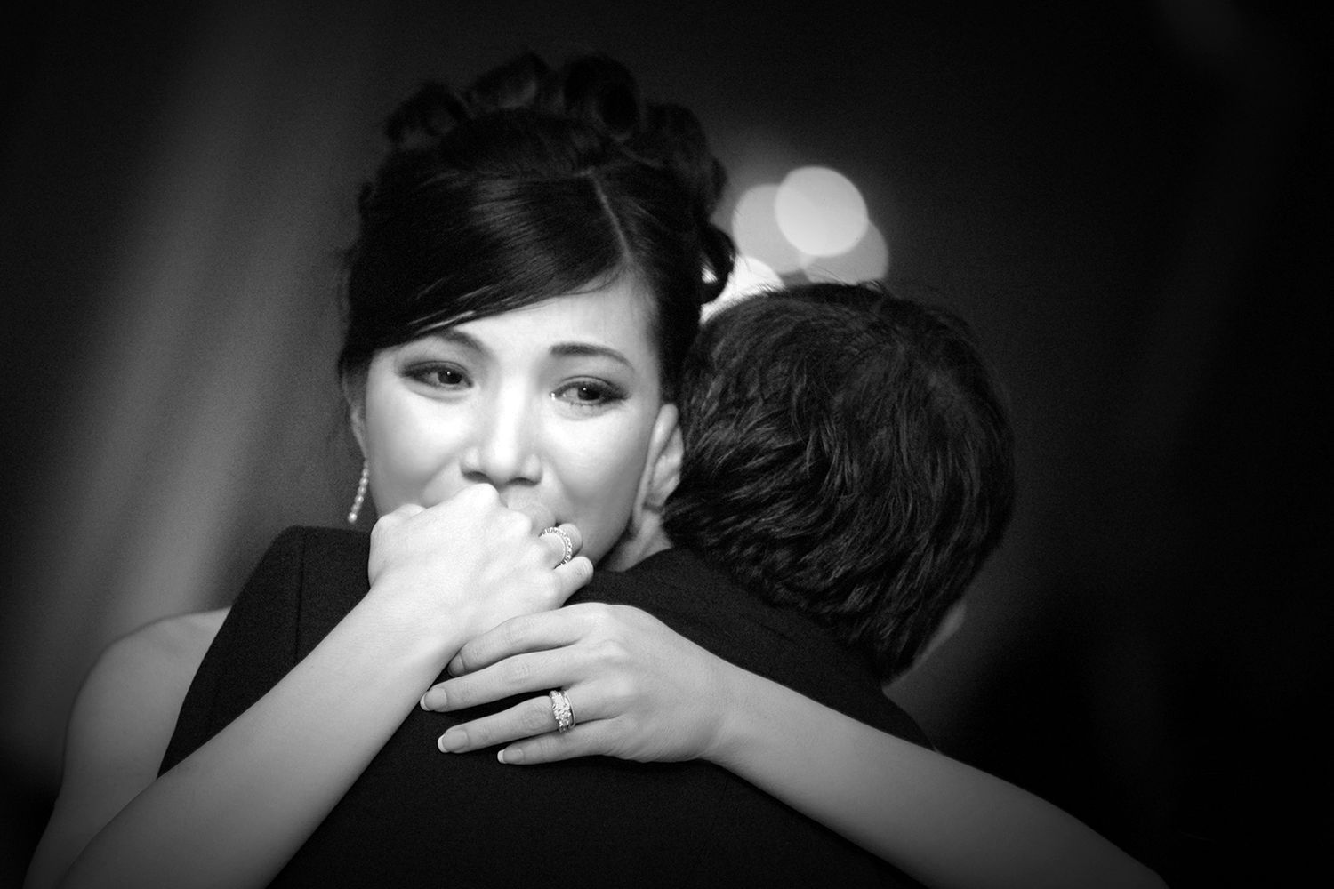 Intimate black and white portrait captures an emotional embrace during wedding celebration.