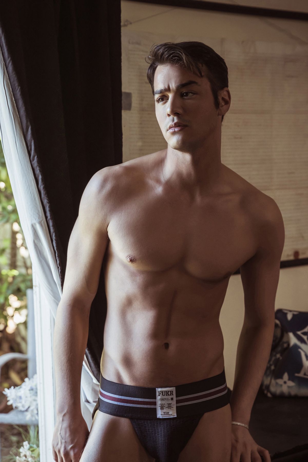 Male model in dark underwear posing in interior setting.