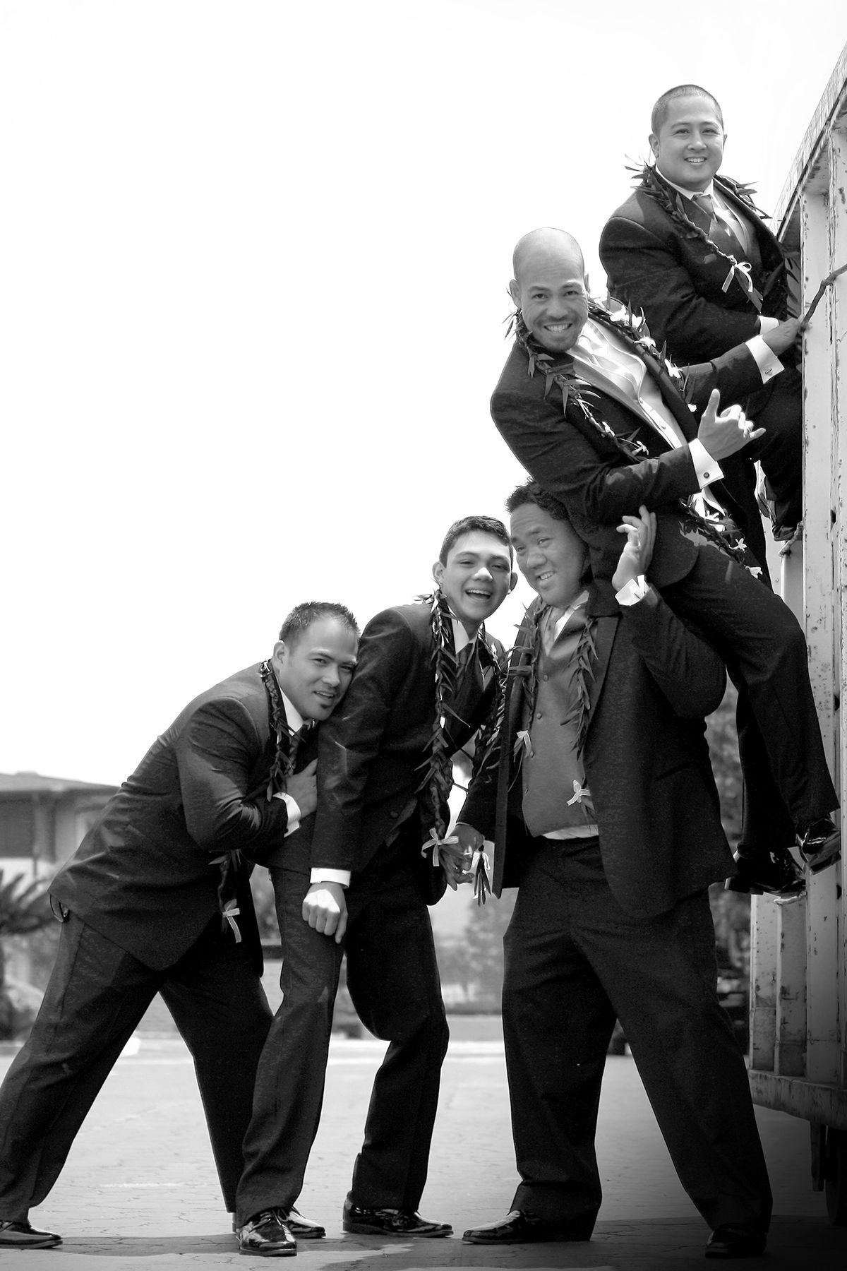 Fun black and white photo of groomsmen striking playful poses together in formal attire.