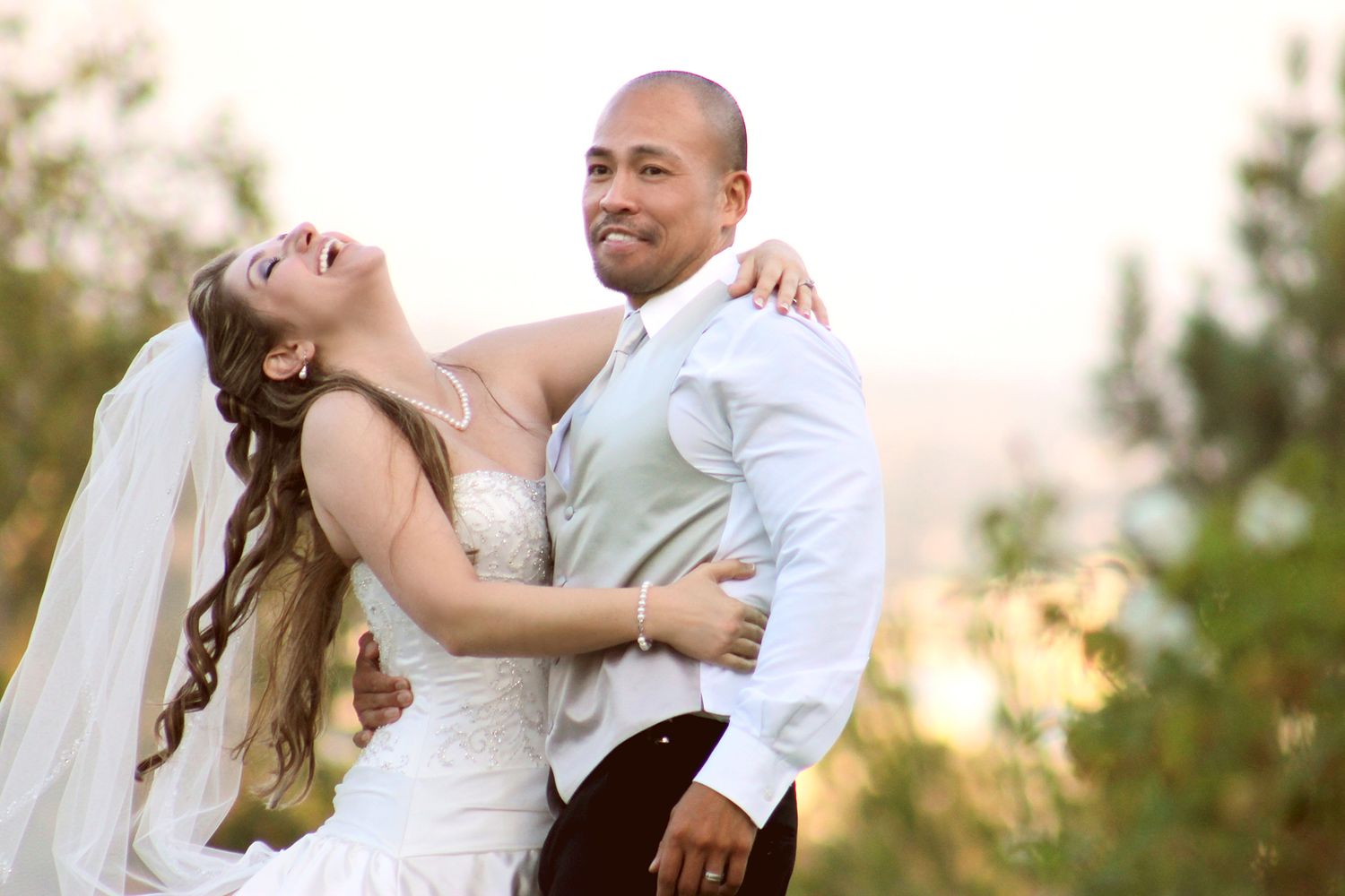 A couple shares a joyful candid moment together outdoors during their wedding celebration.