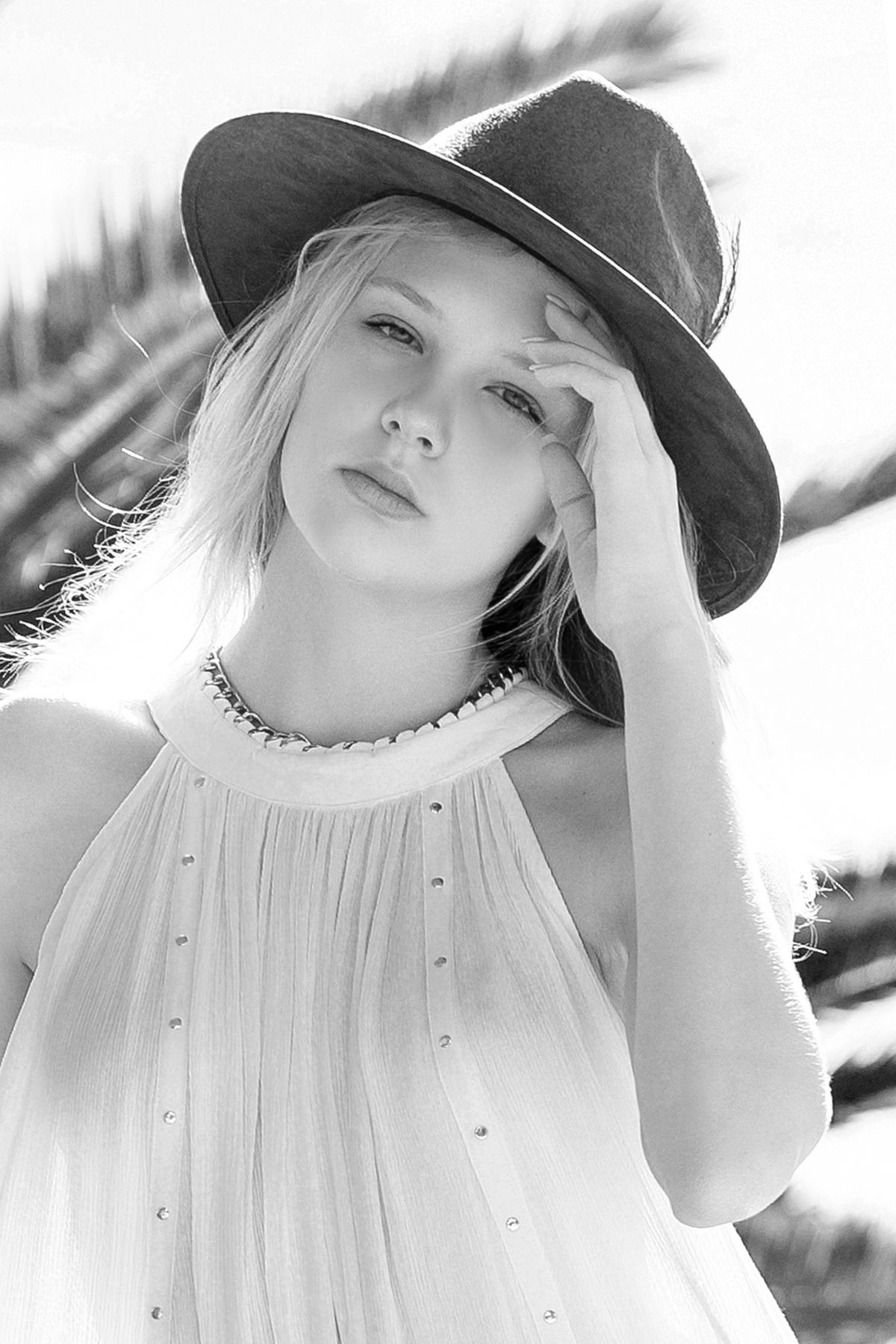 Black and white portrait of model in hat and flowing dress outdoors.