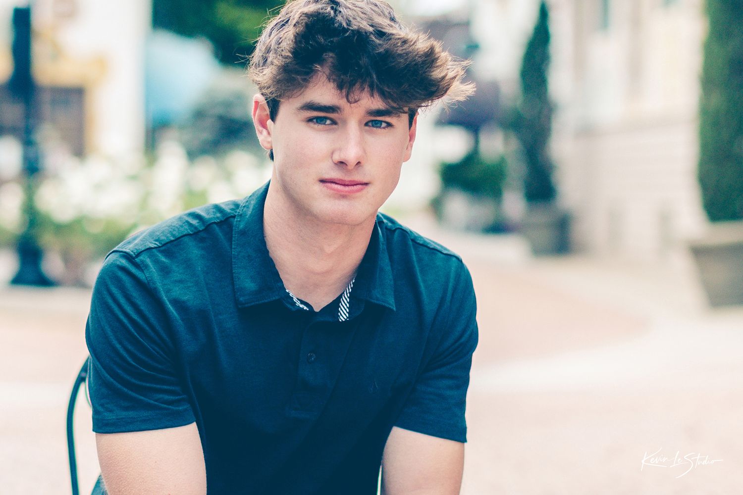 Casual portrait series of someone in a blue polo shirt against architectural background.
