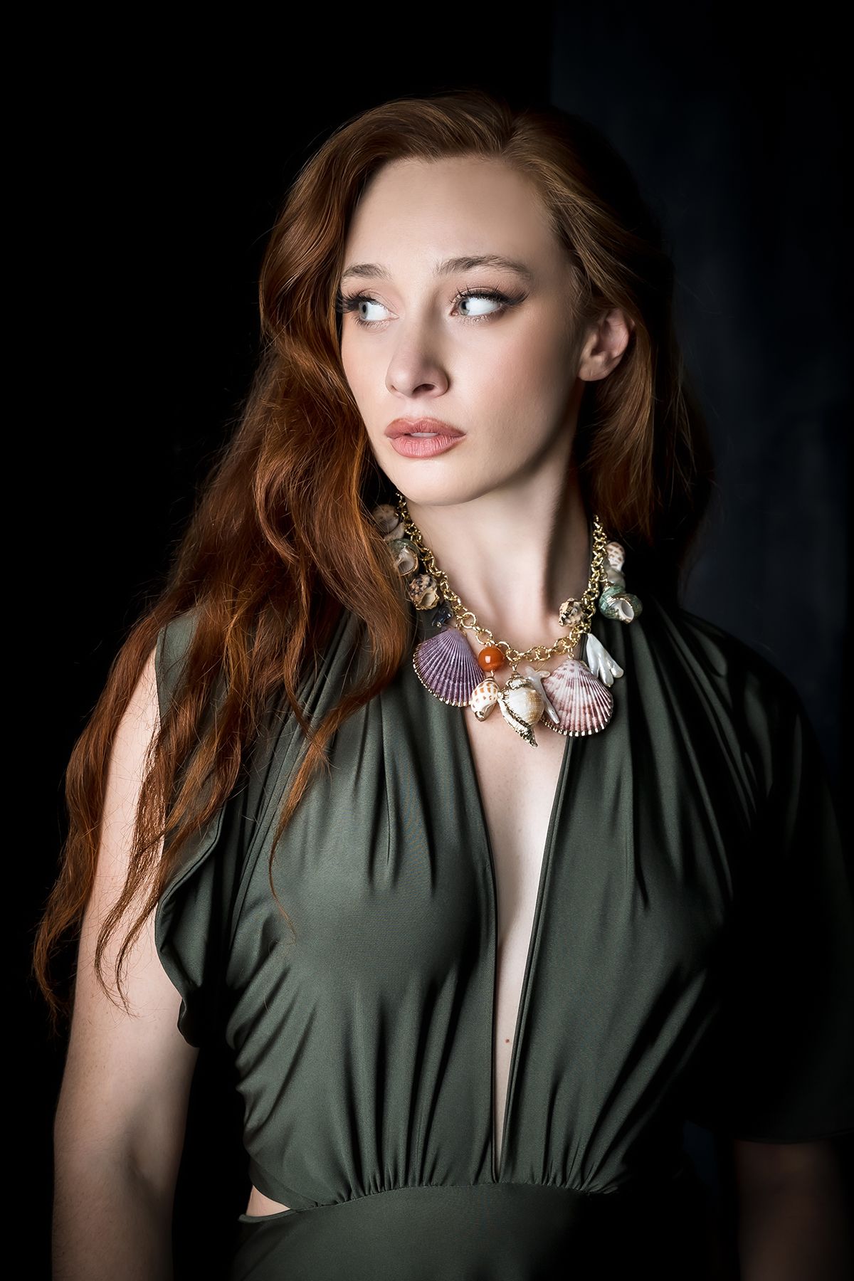 Dramatic portrait in olive green dress with seashell statement necklace.
