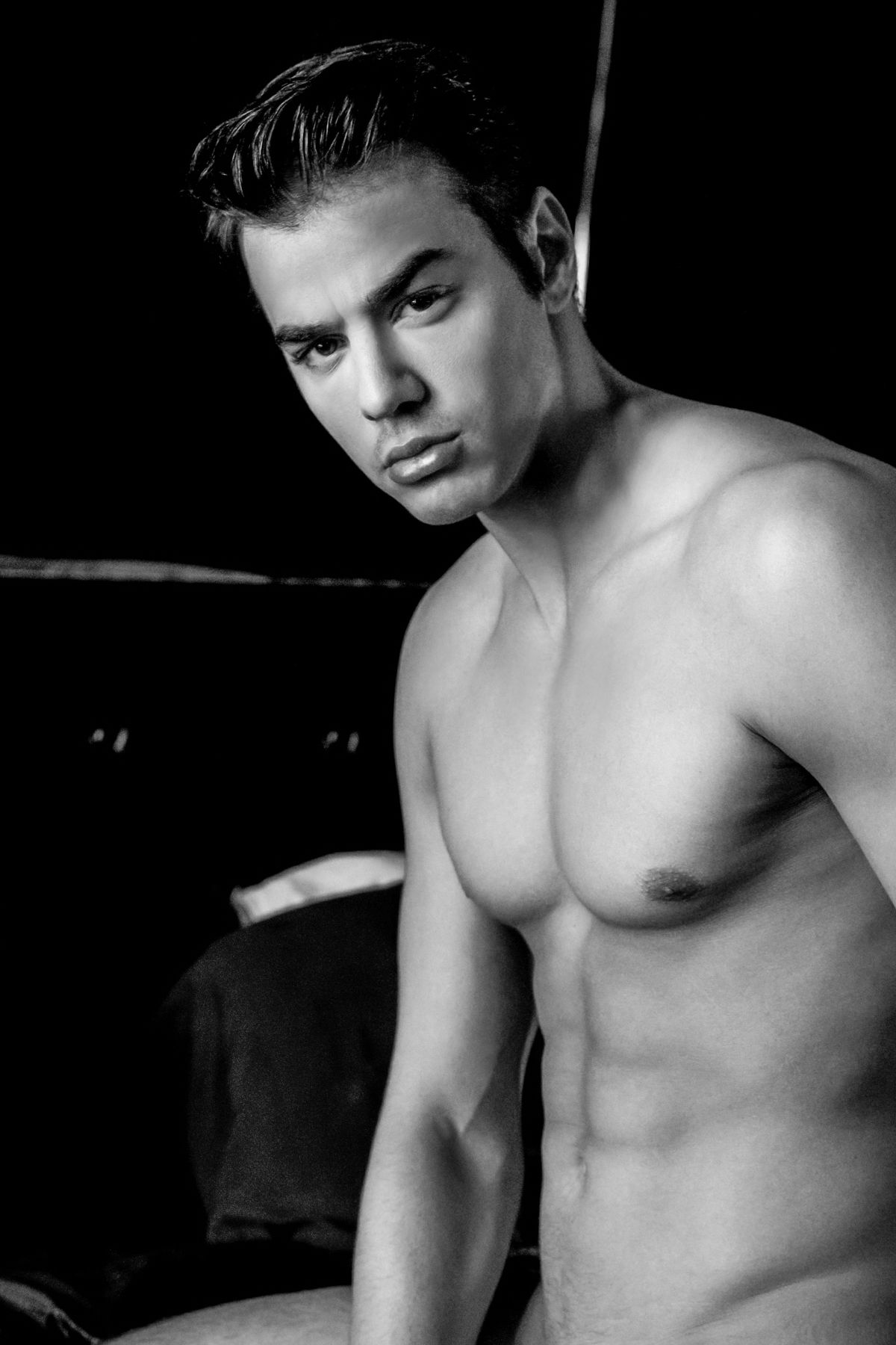Moody black and white portrait of athletic male model in studio setting.