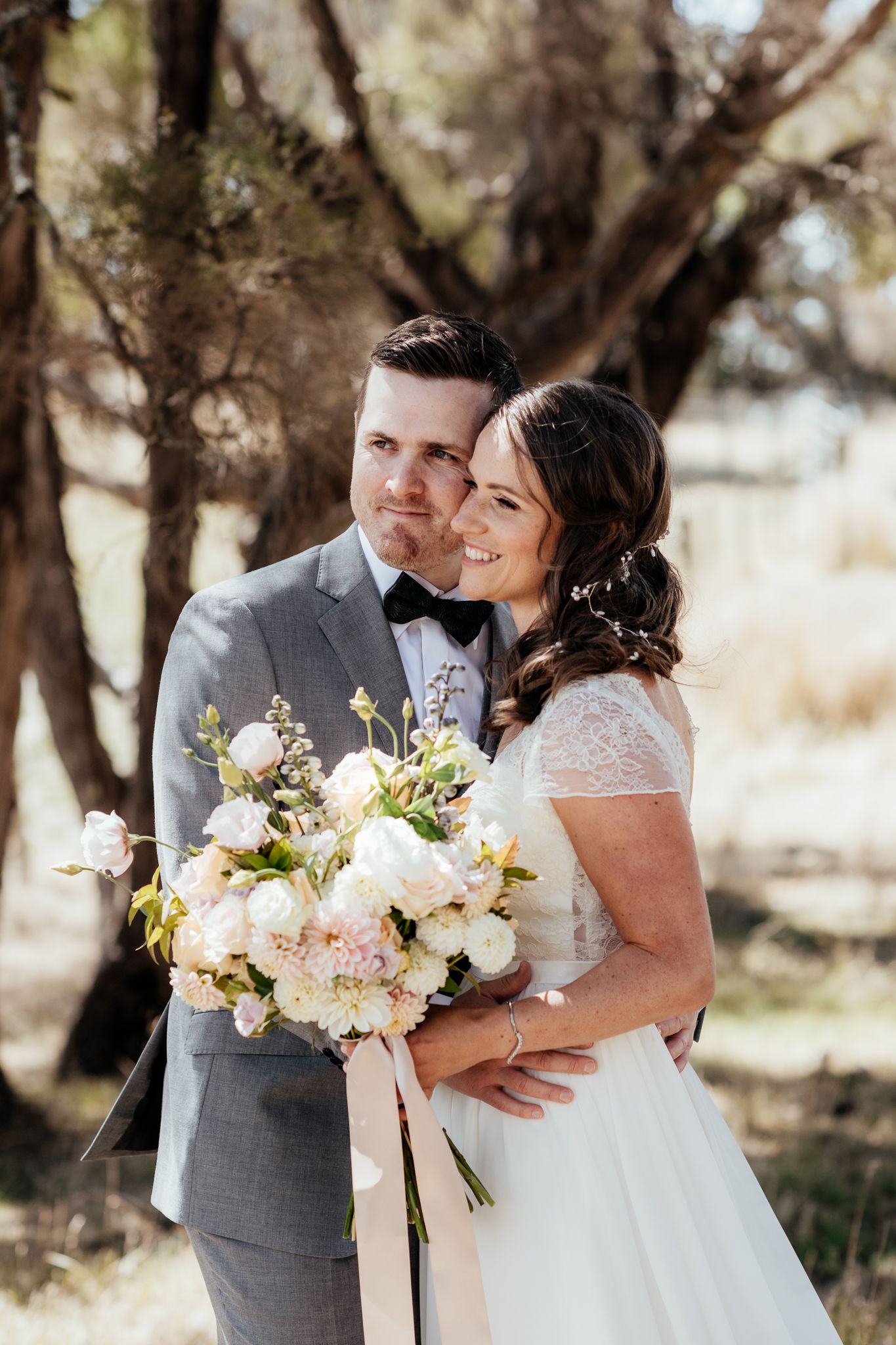 Elegant couple sharing intimate moment outdoors with stunning white floral bouquet on their wedding day by August and Vine
