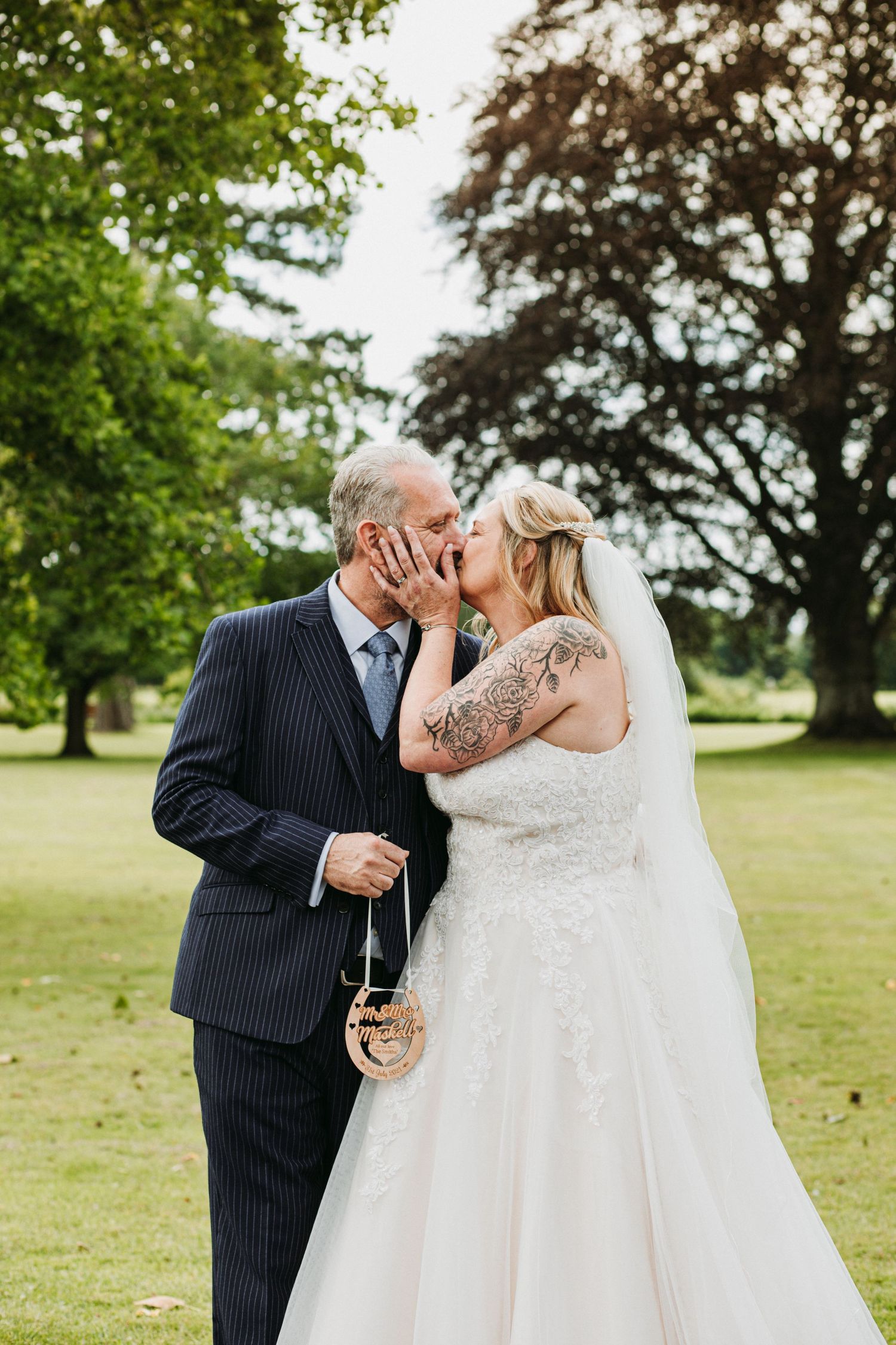 Newlyweds share an intimate moment outdoors as the bride touches her groom's face while he holds champagne.