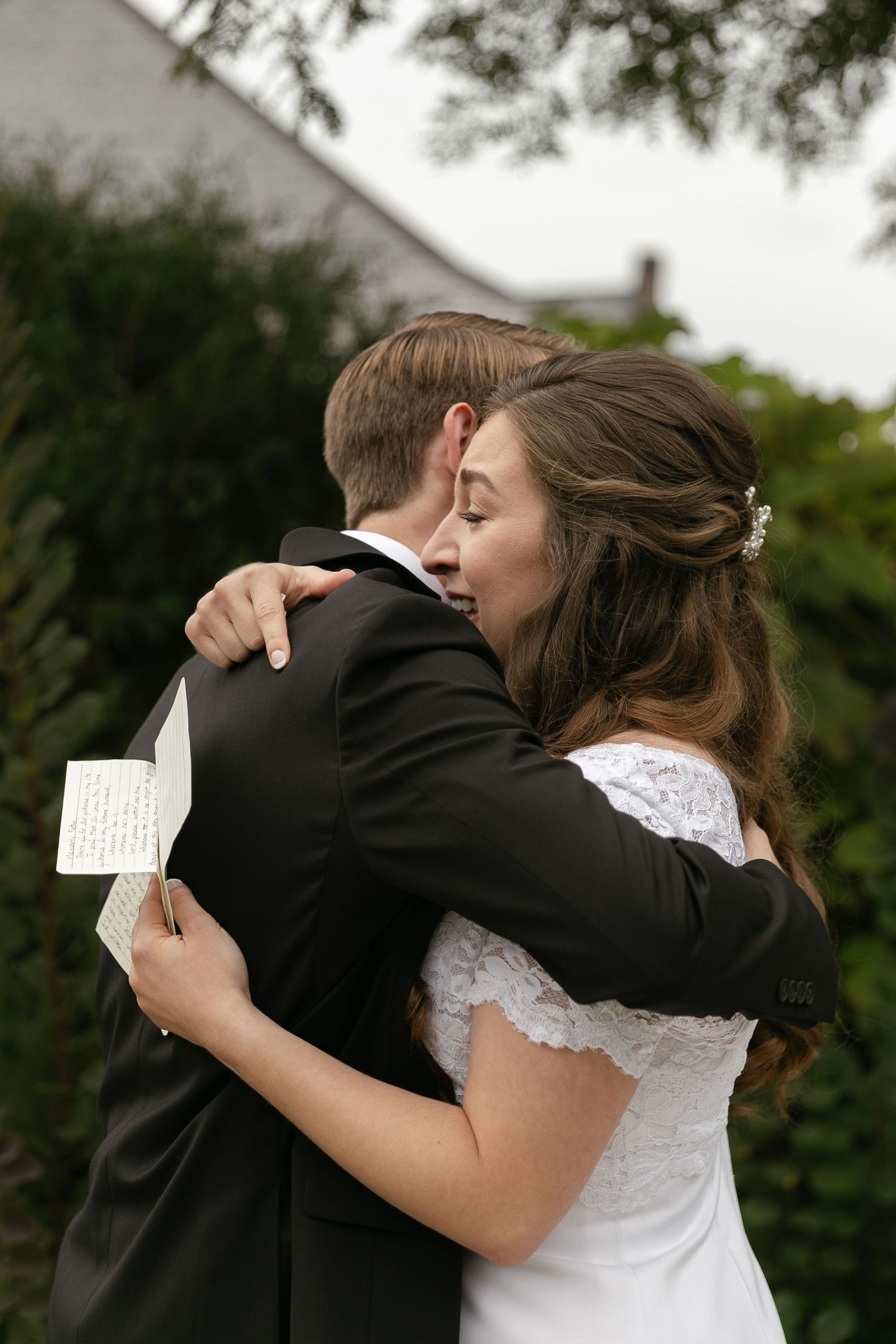 Series of tender embraces and emotional moments of a couple sharing handwritten notes during a wedding ceremony outdoors.