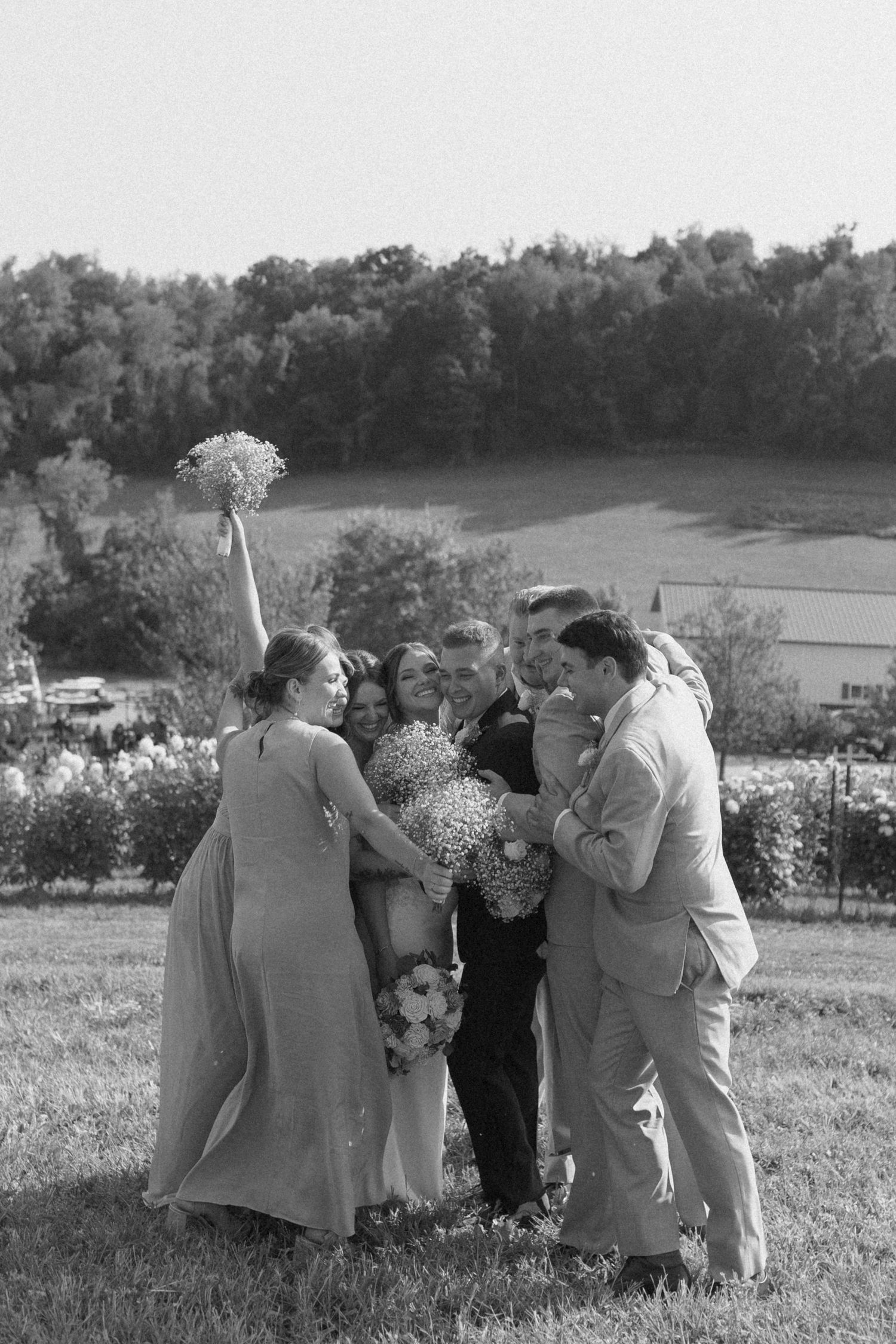 Group gathered outdoors at a scenic hillside location during a casual black and white ceremony.